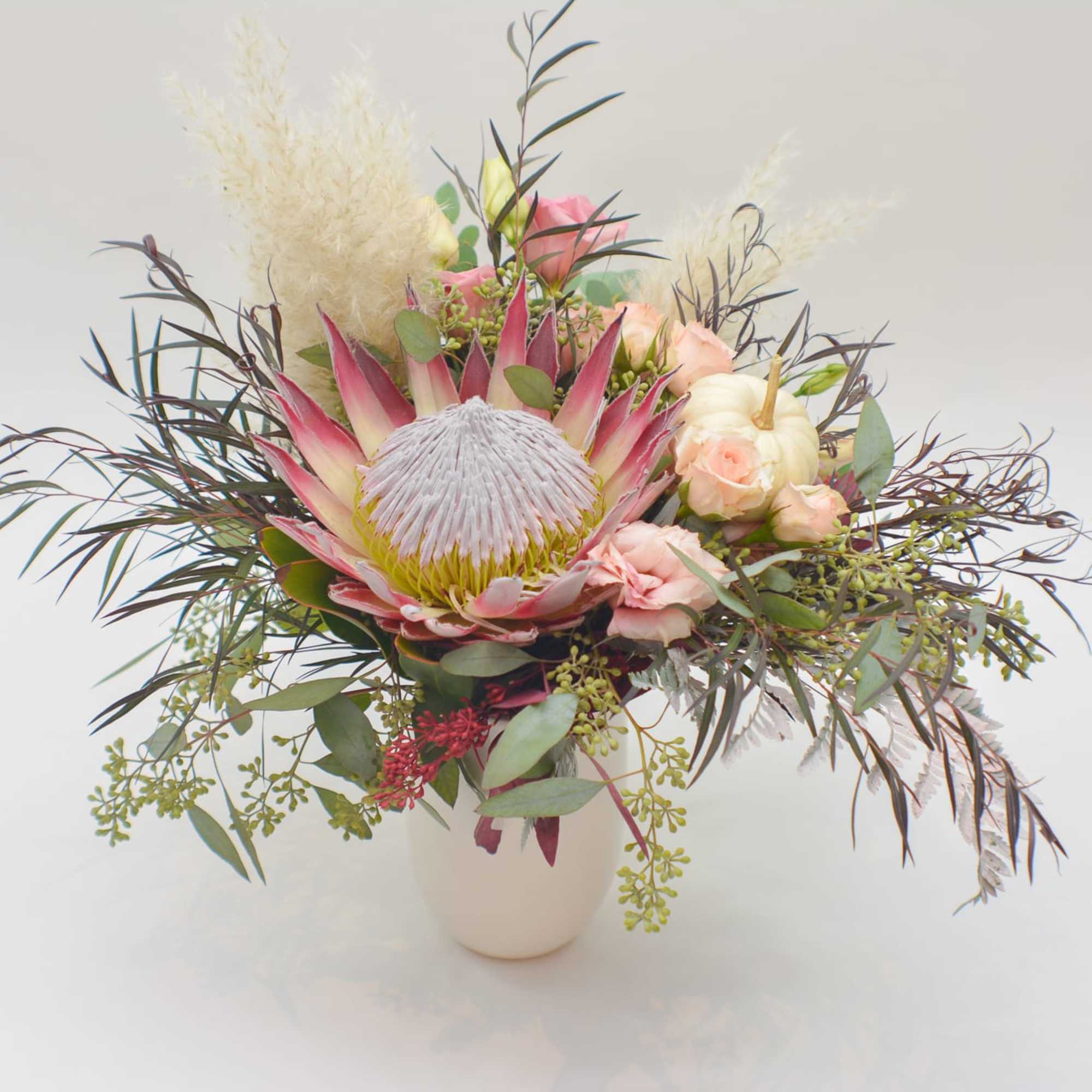Mixed bouquet with a large pink protea in a white vase