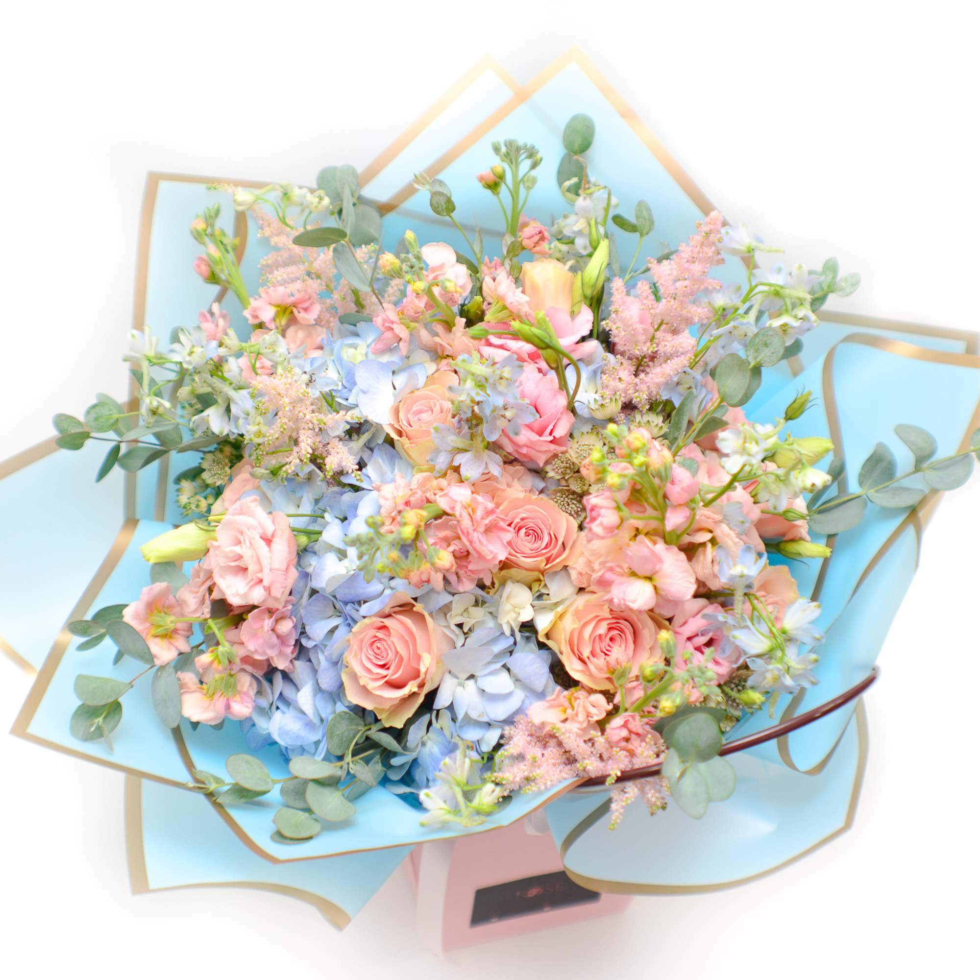 Pastel bouquet of pink roses and blue hydrangeas wrapped in blue paper