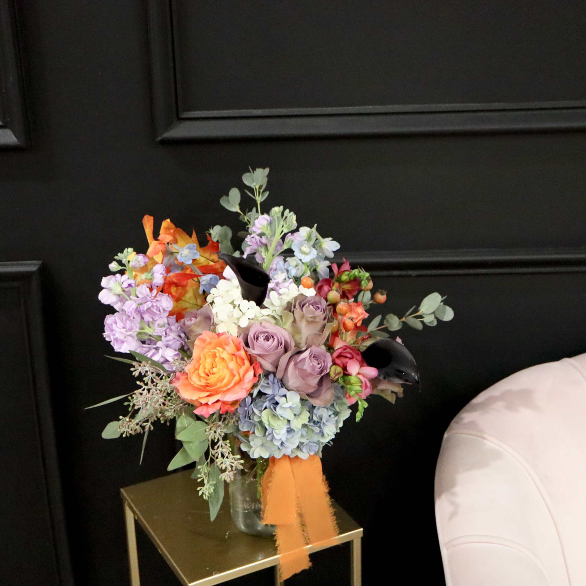 Colorful bouquet in a glass vase with orange ribbon