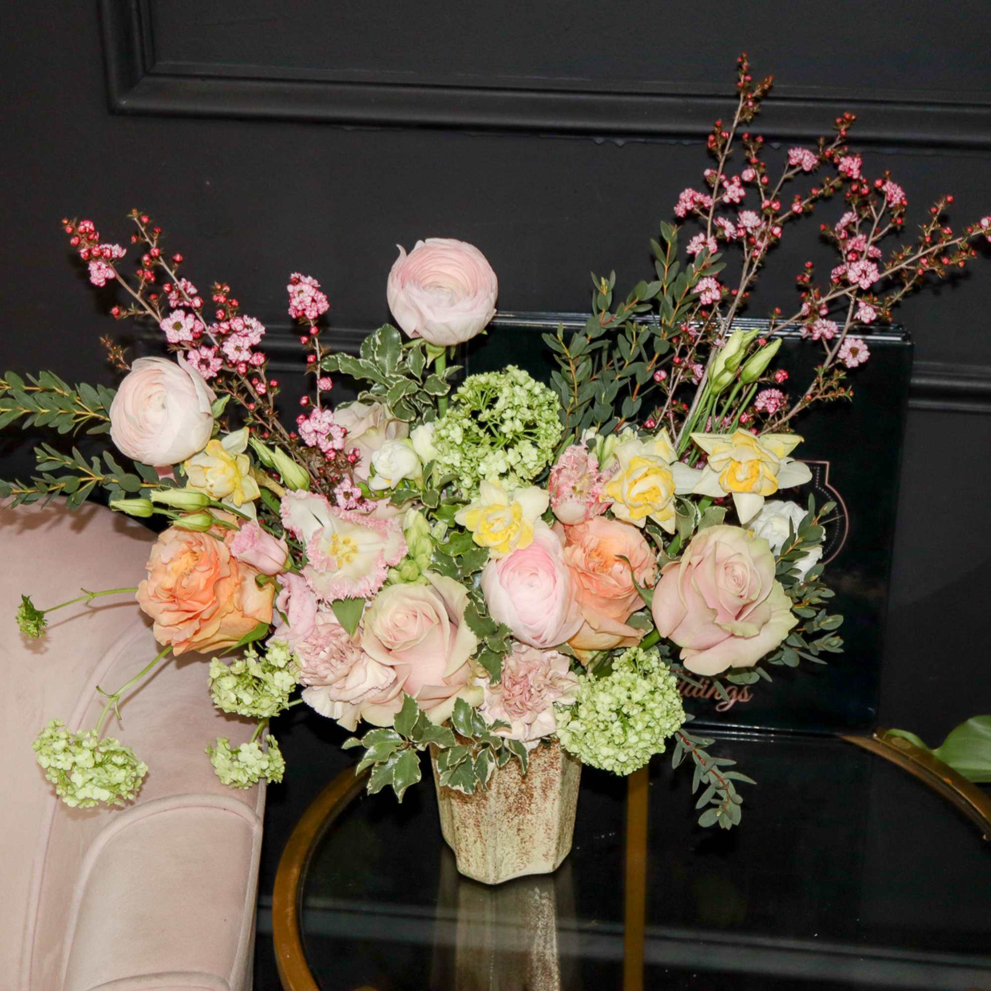 Pastel floral arrangement in a textured vase with pink and peach blooms