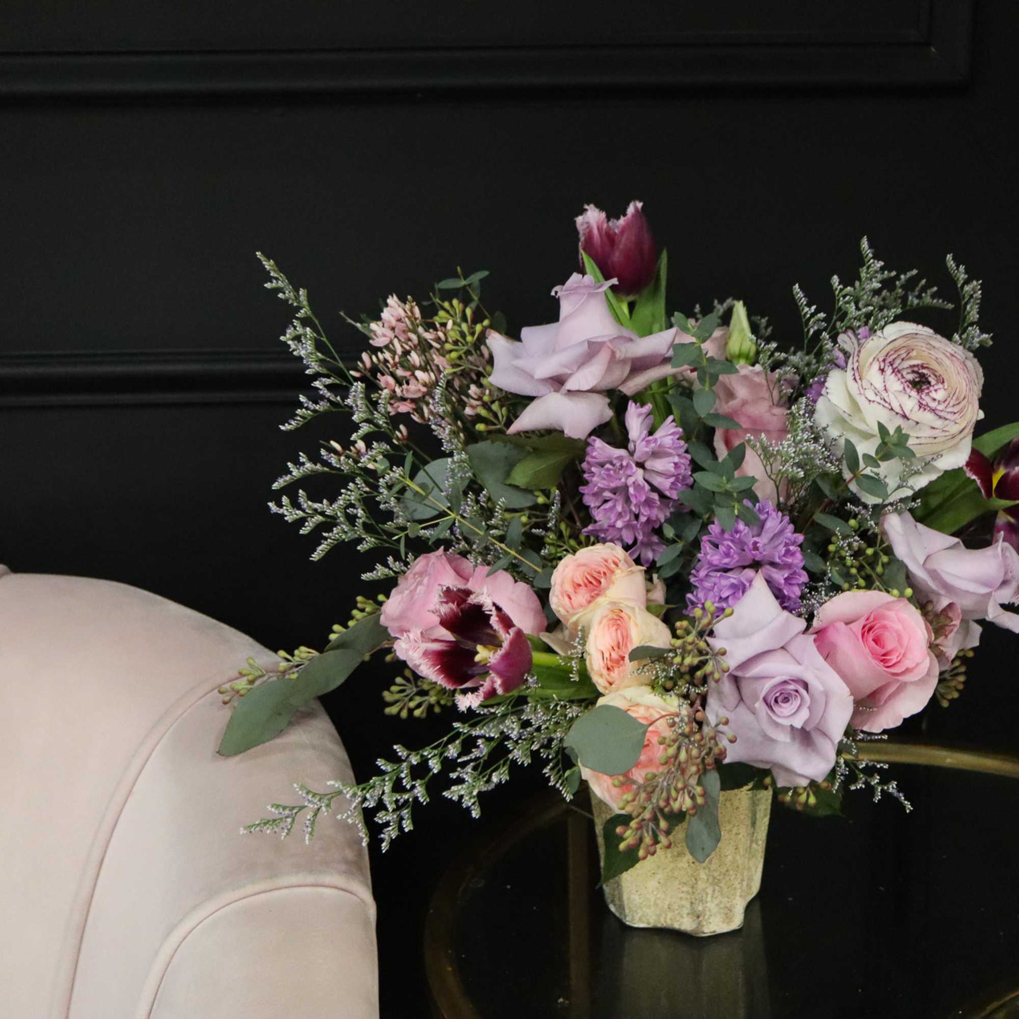 Mixed bouquet of pink and lavender flowers in a small vase