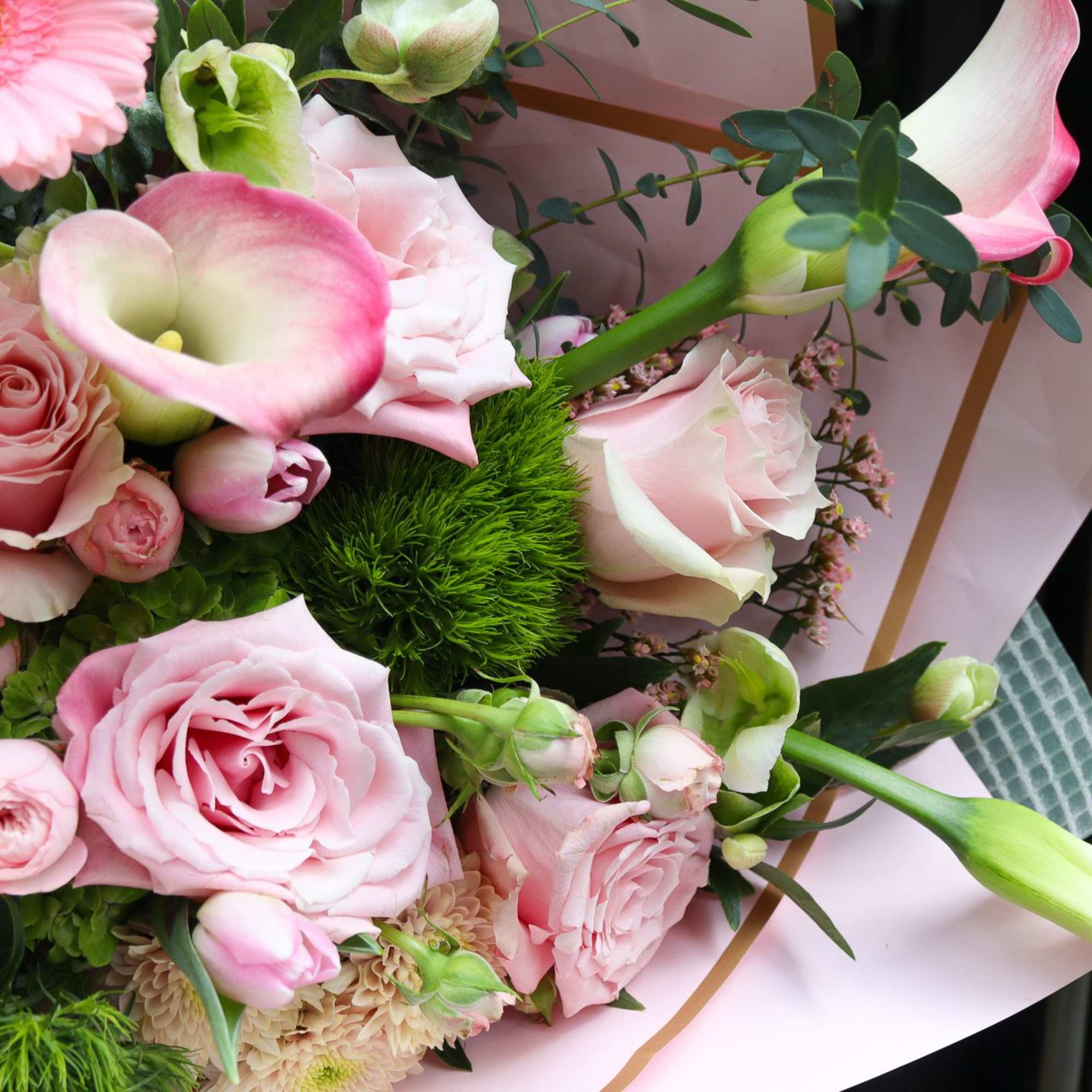 Pink roses and calla lilies in a hand-tied bouquet