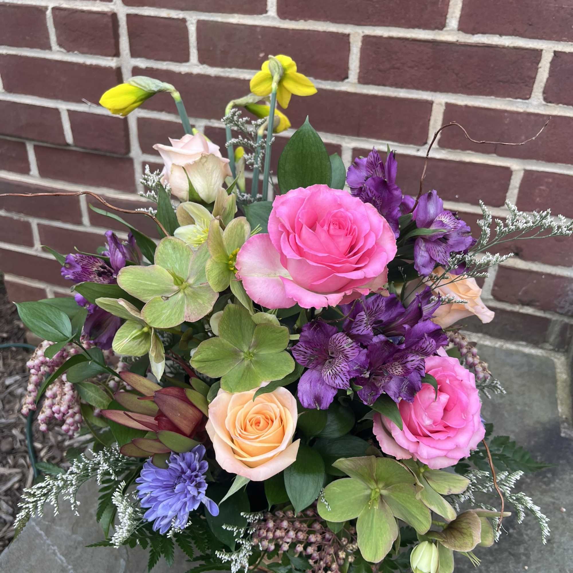 Mixed bouquet with pink and peach roses, purple blooms, and green hydrangea-like flowers