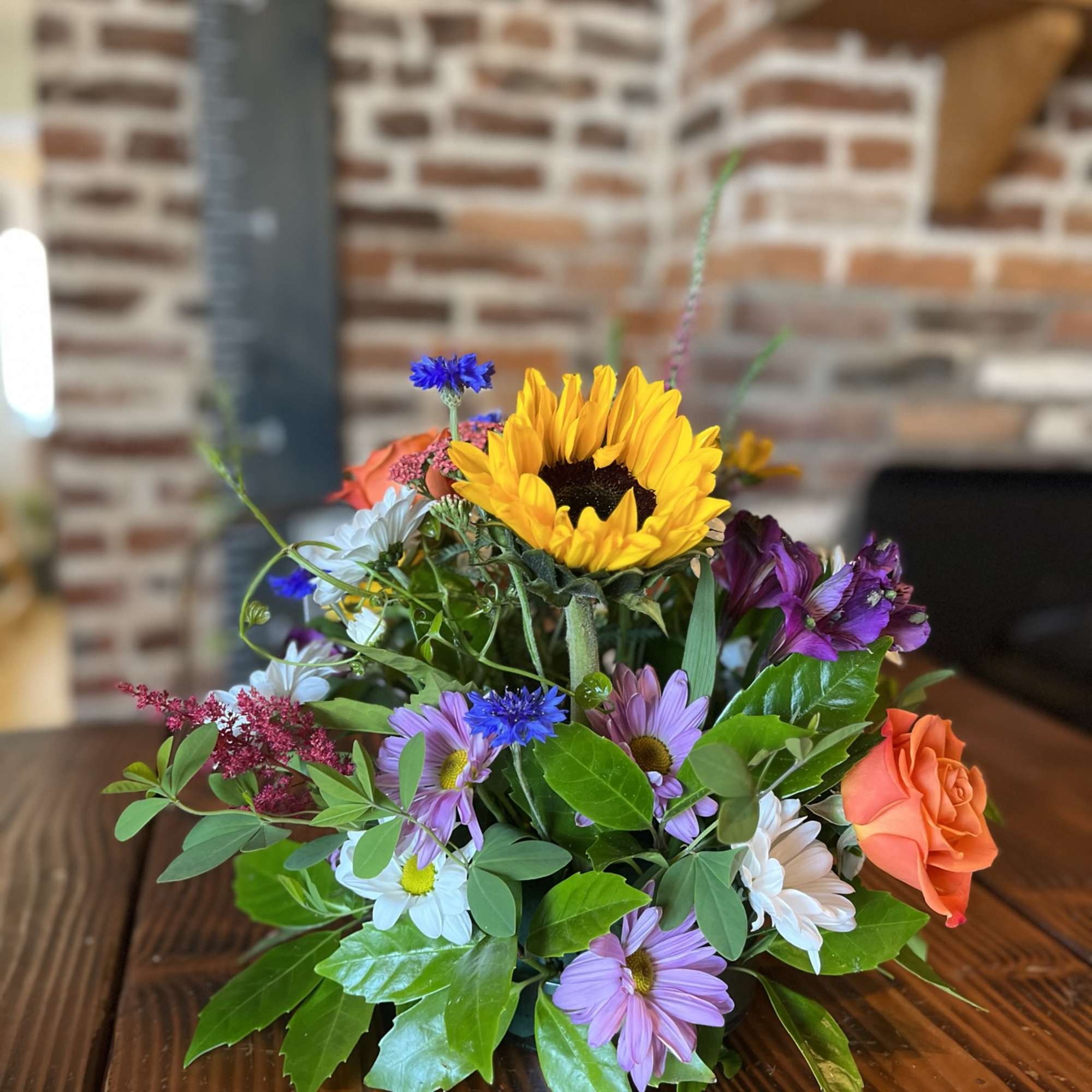 Mixed bouquet with a sunflower, roses, and daisies on a table