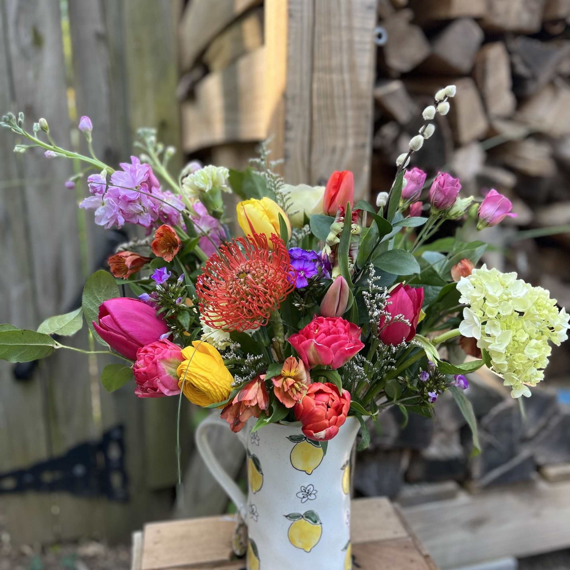 Colorful mixed bouquet in a lemon-patterned pitcher vase