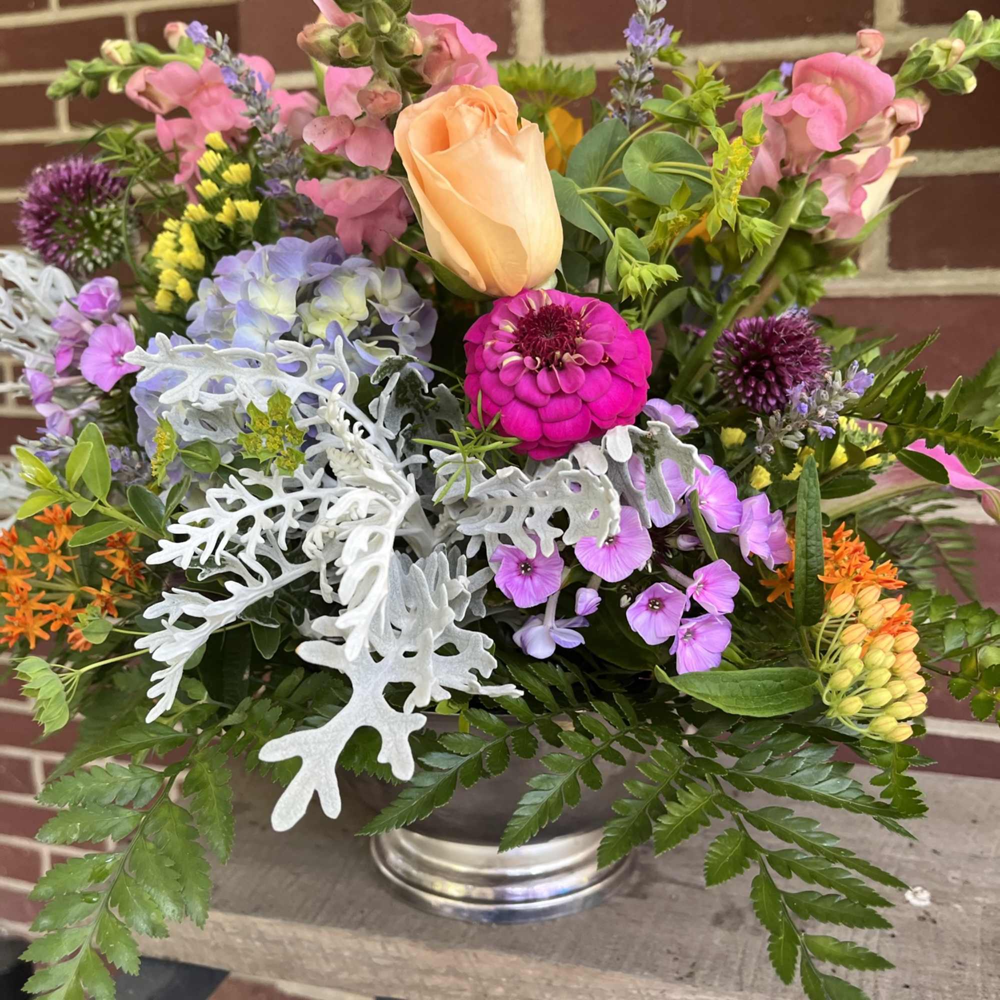 Mixed bouquet in a silver vase with peach, pink, purple, and orange flowers