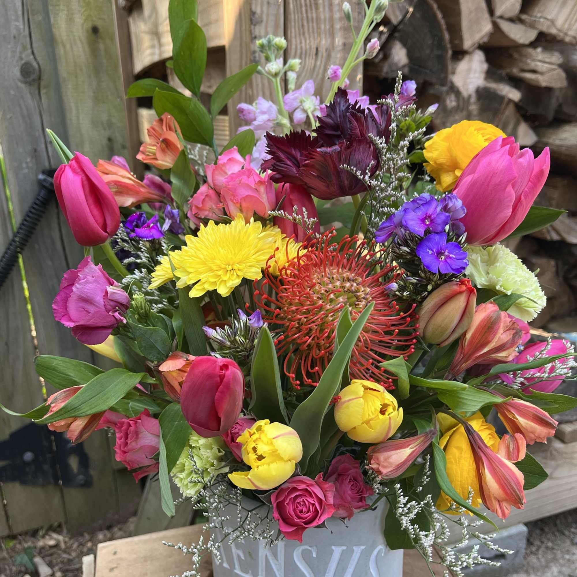 Colorful mixed bouquet in a gray bucket with tulips, roses, and chrysanthemums