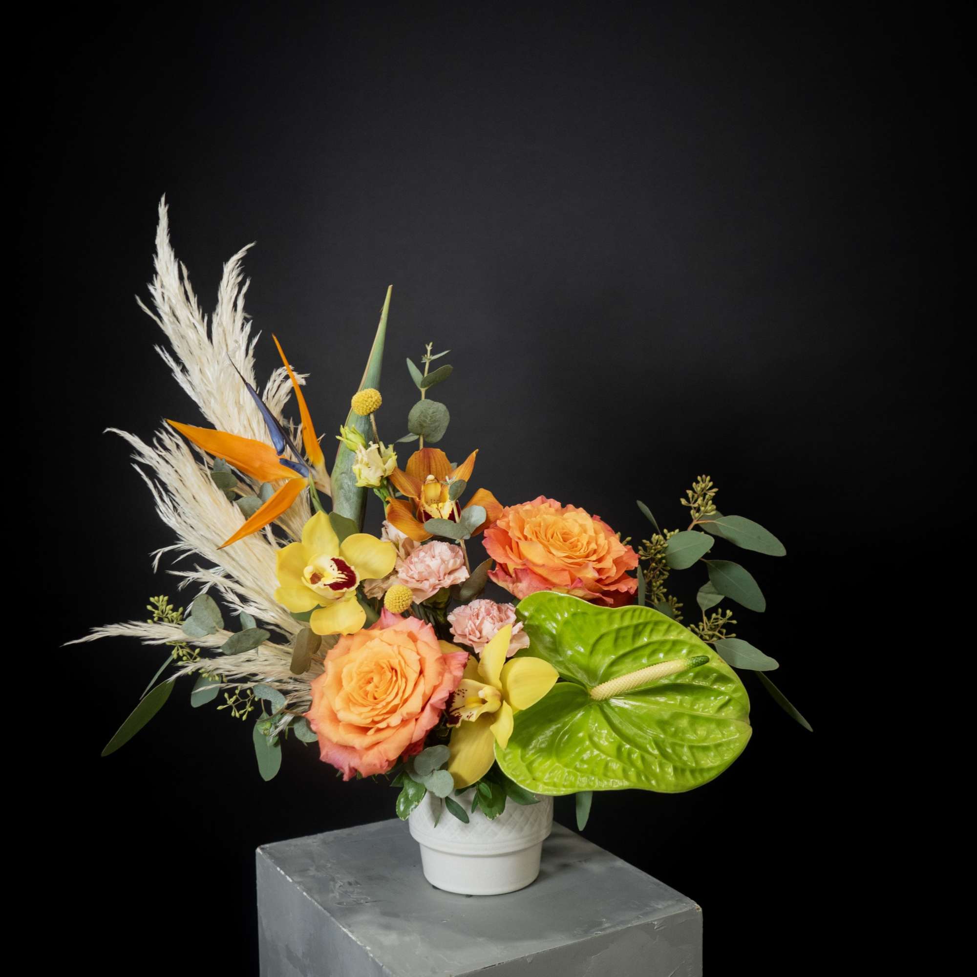 Tropical bouquet with orange roses and yellow orchids in a white vase