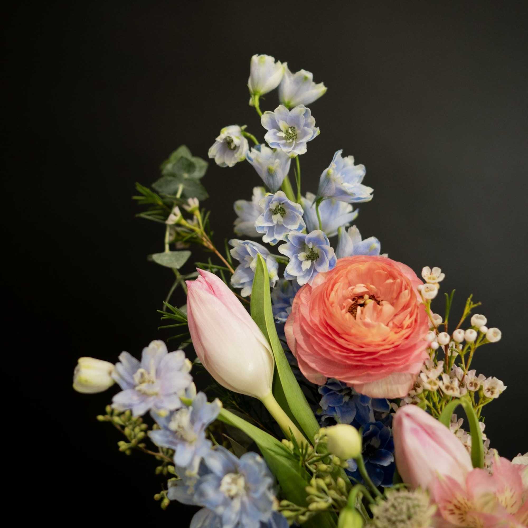 Bouquet with pink ranunculus, tulips, and blue flowers