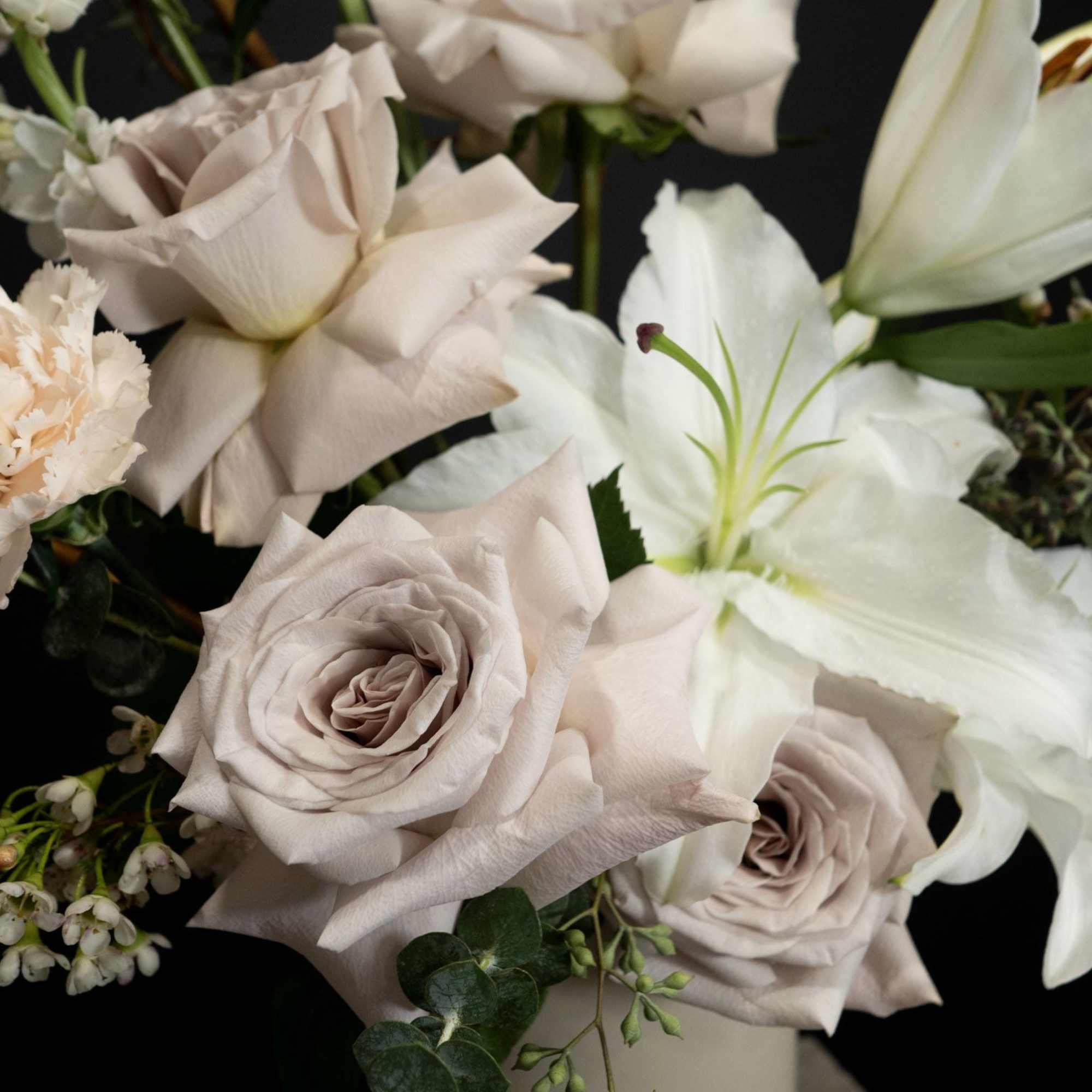 Bouquet of pale roses and white lilies in a vase