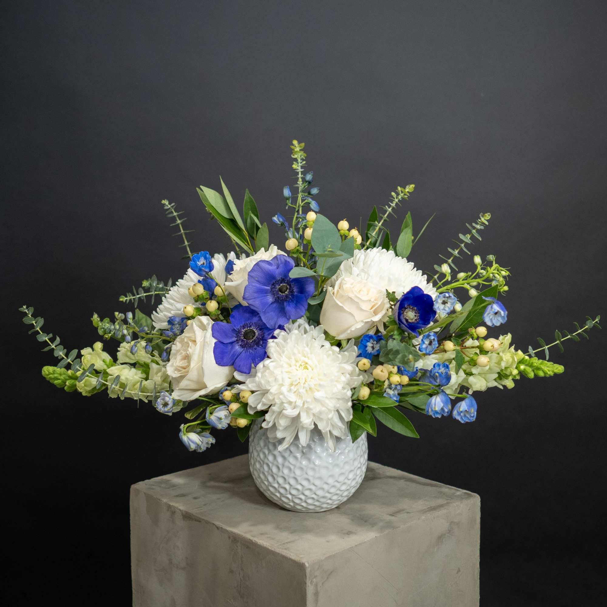 White and blue floral arrangement in a textured white vase