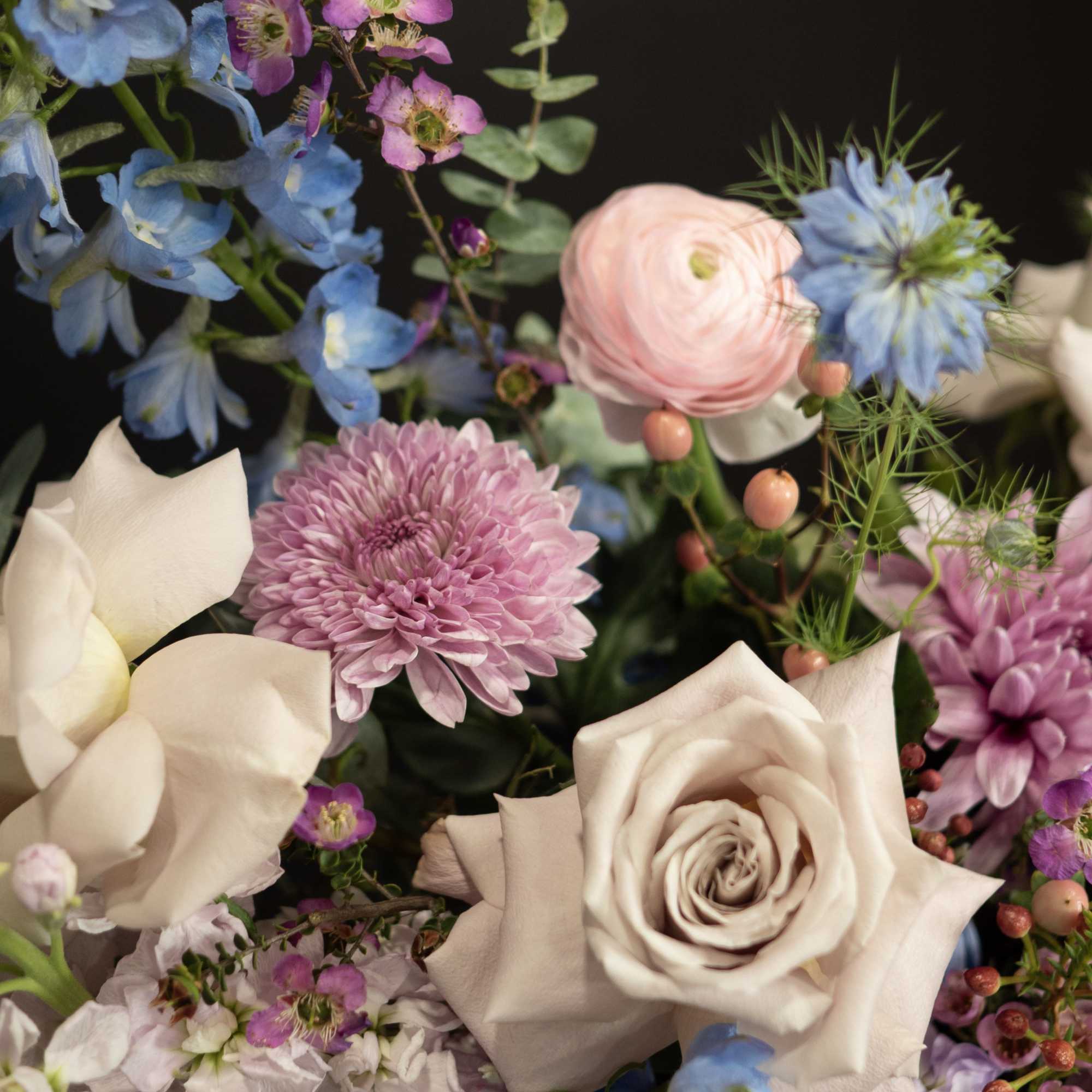 Mixed bouquet with pale roses, pink blooms, and blue flowers