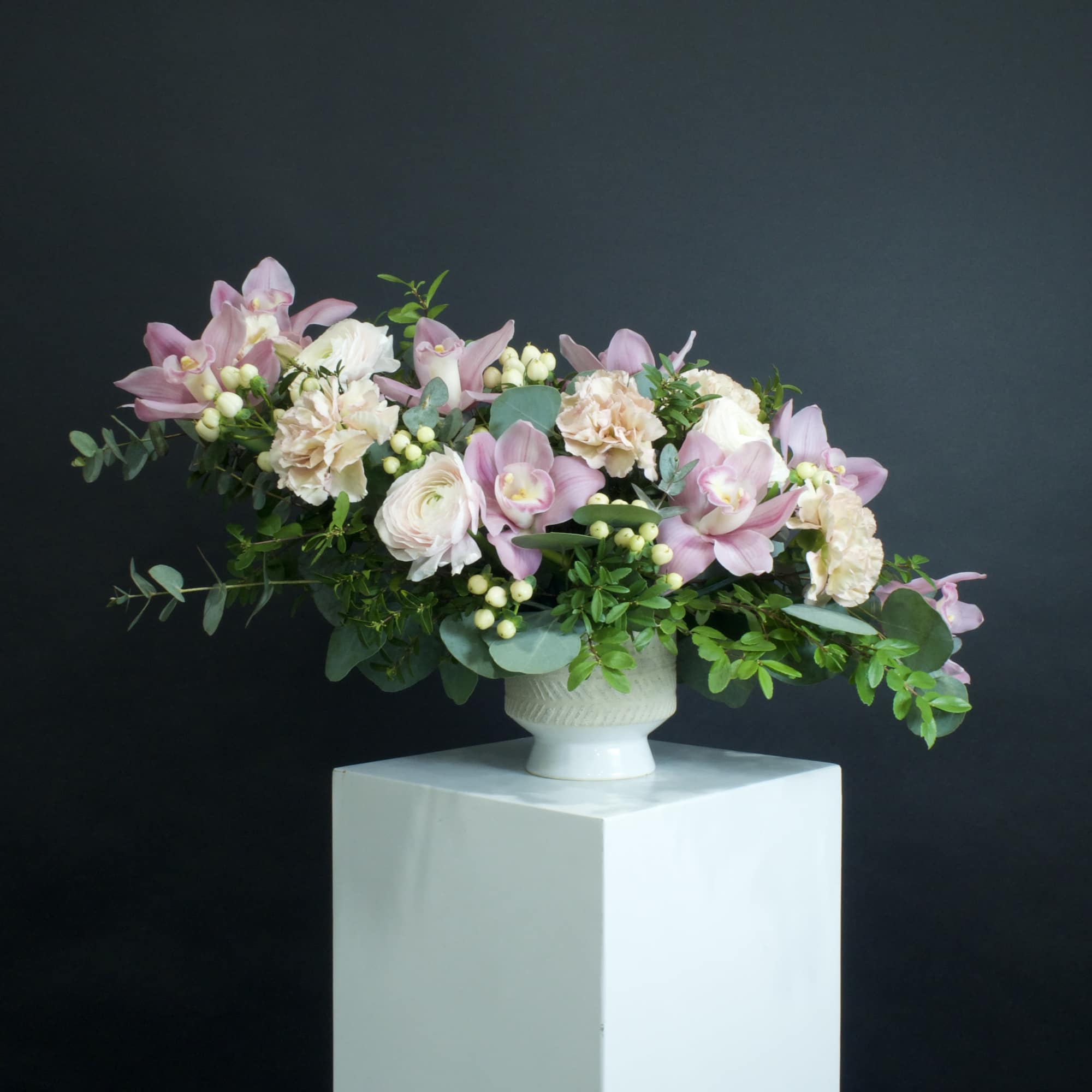Pink and white floral arrangement in a white pedestal vase