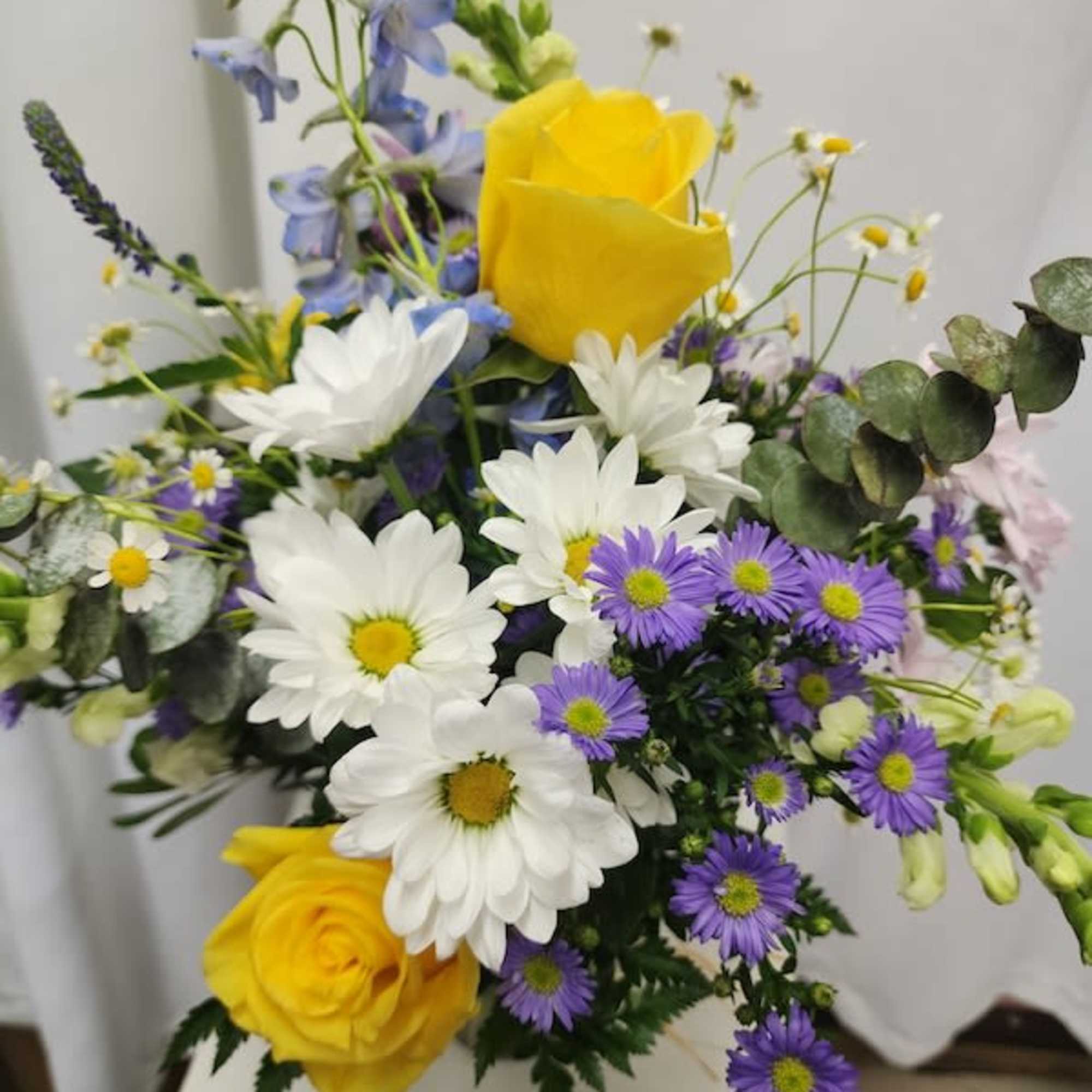 Bouquet of yellow roses, white daisies, and purple flowers