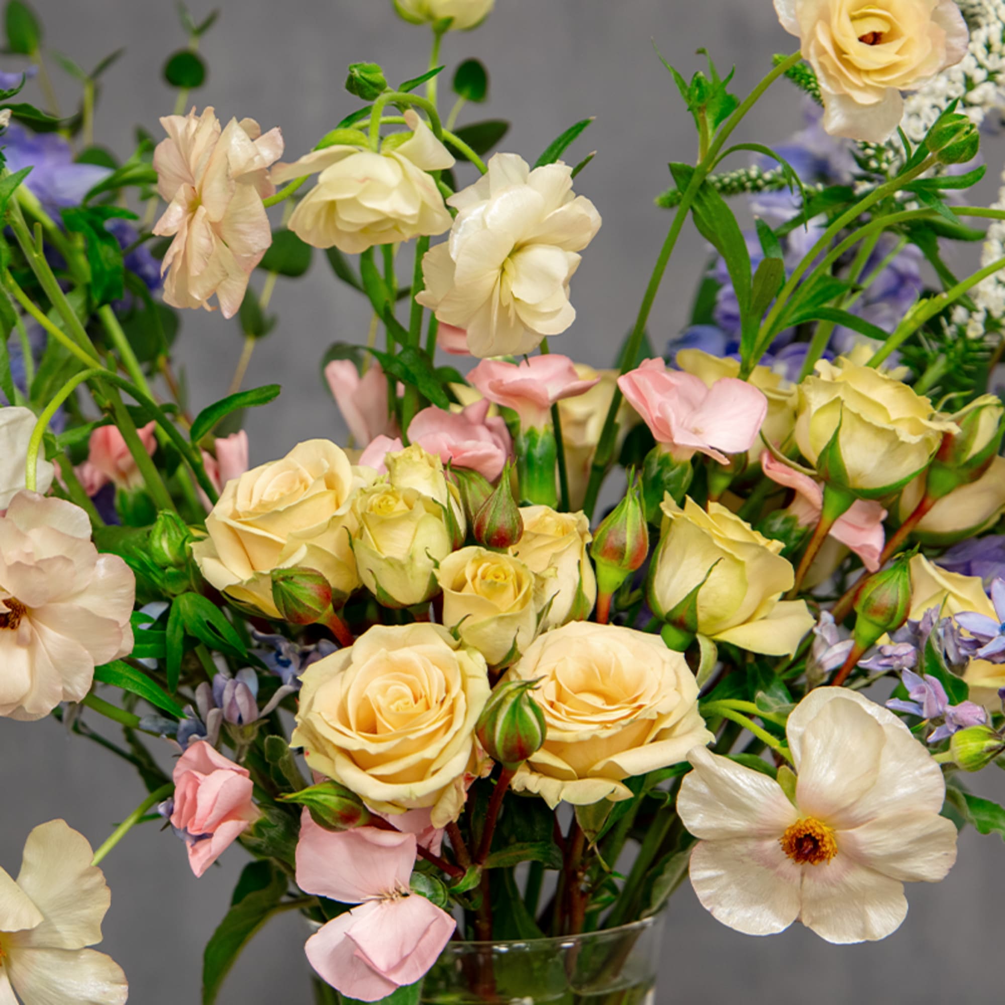 Bouquet of cream roses and pastel blooms in a clear glass vase