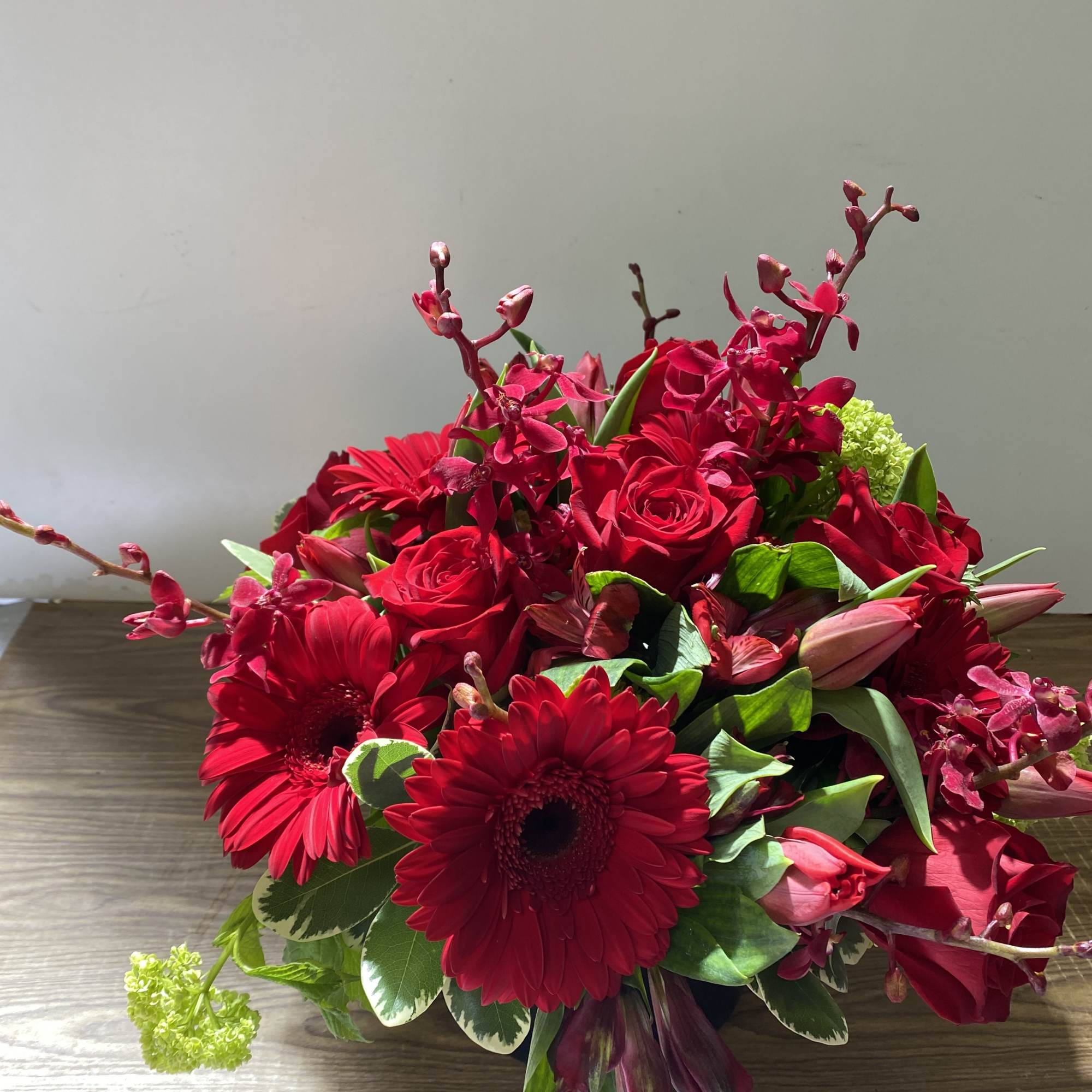 Red bouquet with gerbera daisies, roses, and orchids