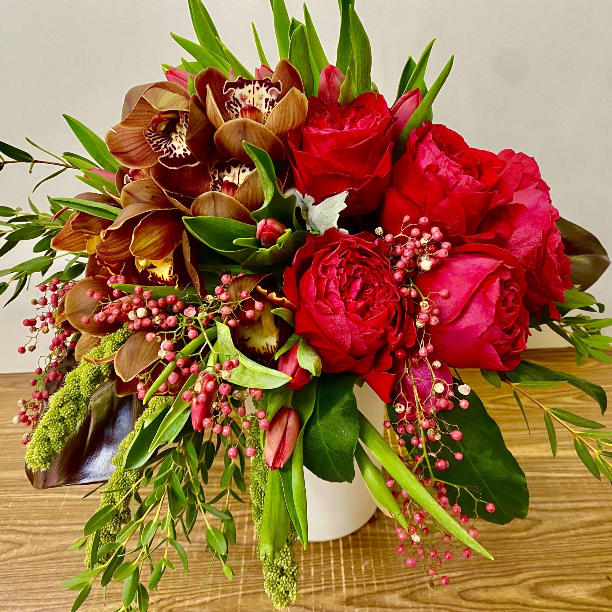 Bouquet of red roses and brown orchids in a white vase