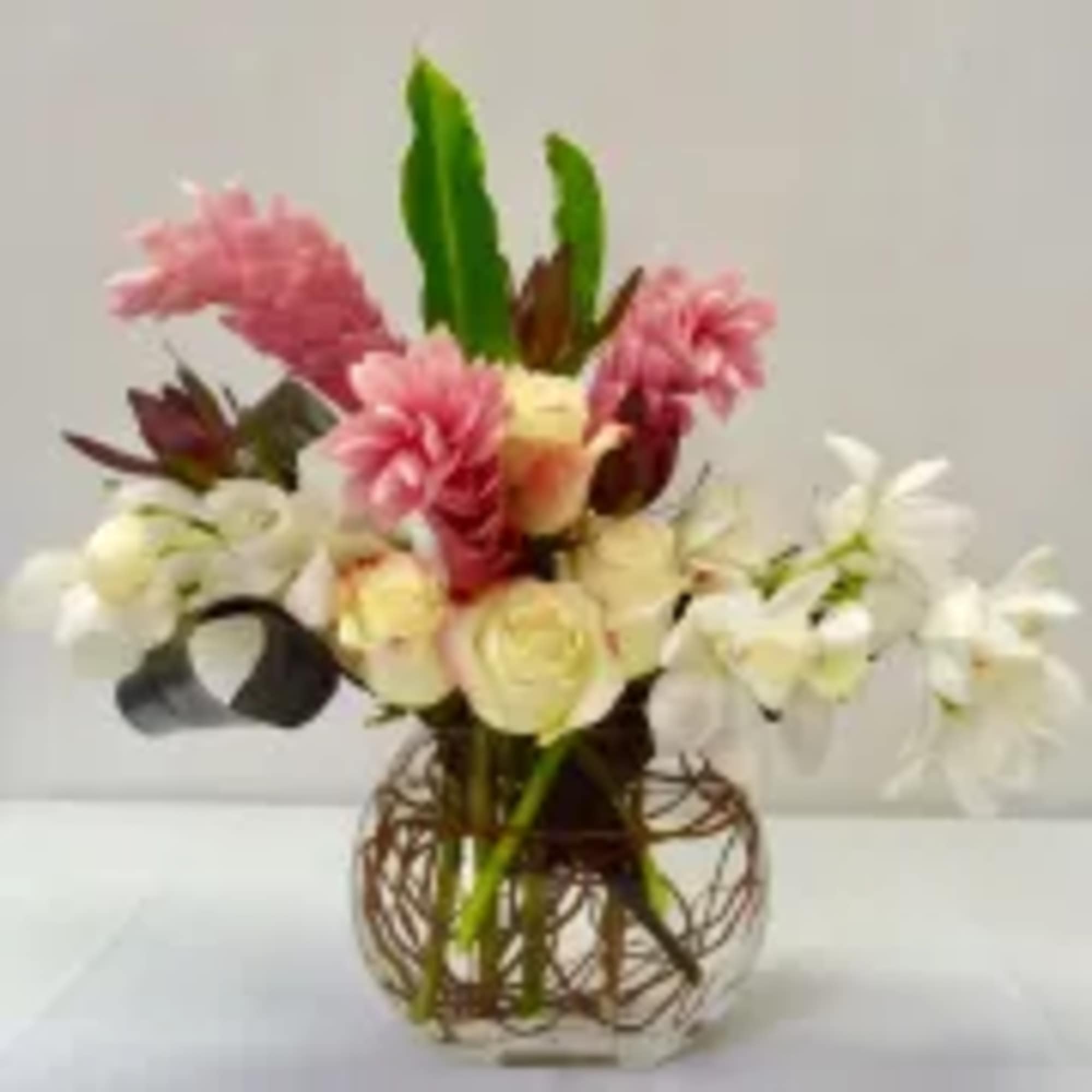 Pink and white floral arrangement in a decorative round vase