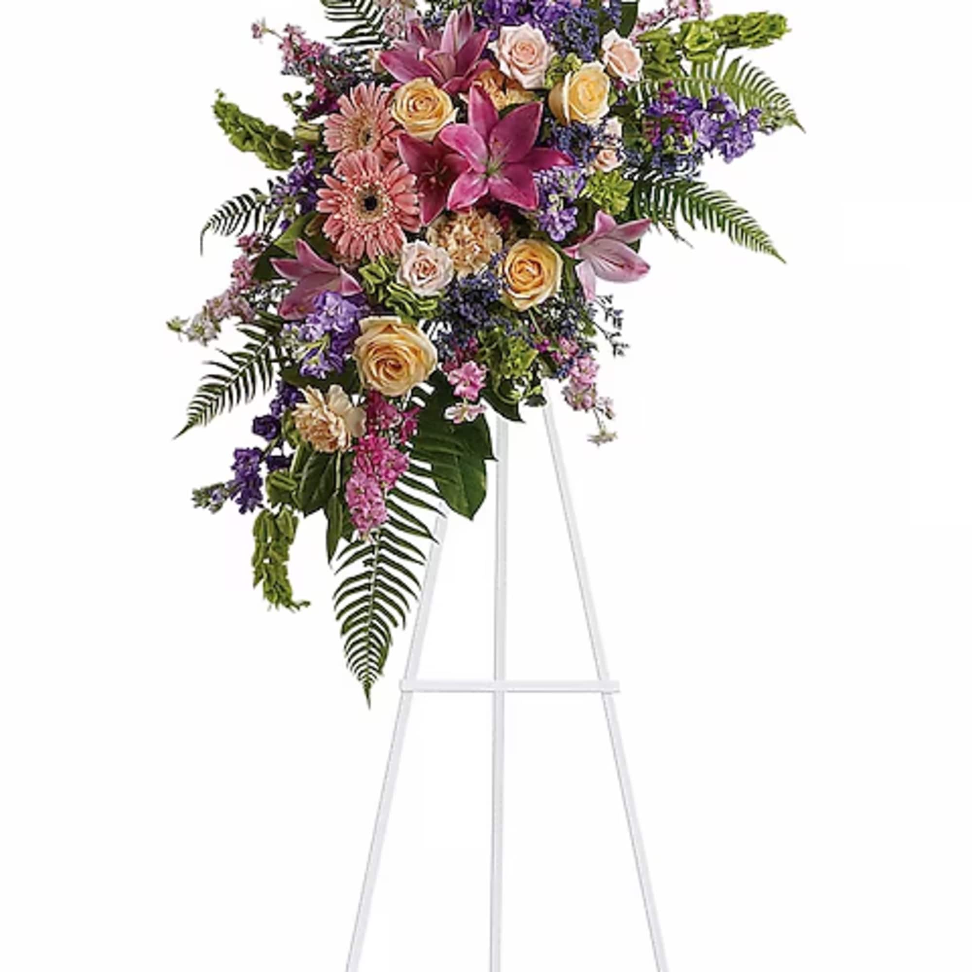 Tall floral spray with pink, purple, and peach blooms on a white easel