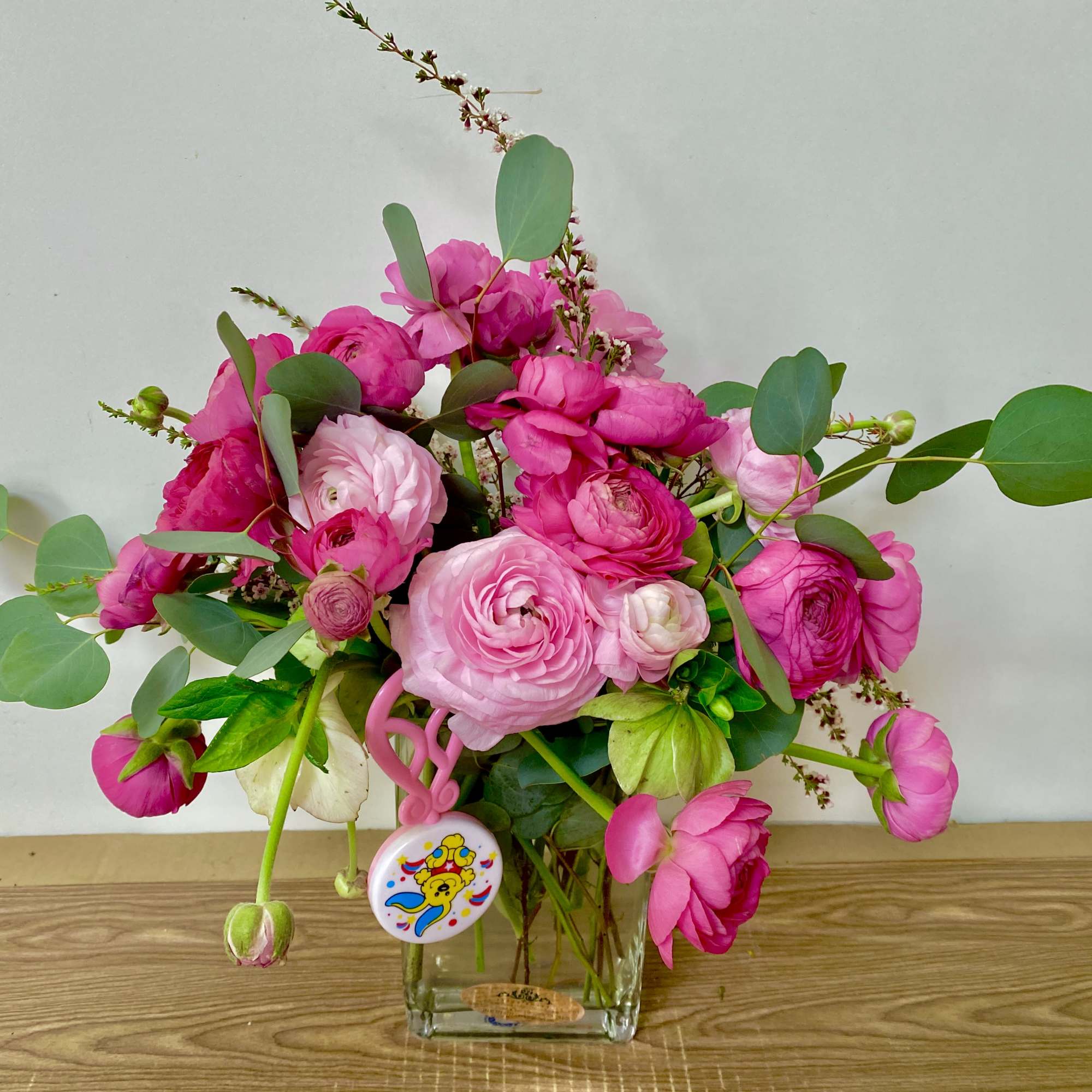 Pink ranunculus bouquet in a clear glass vase with eucalyptus