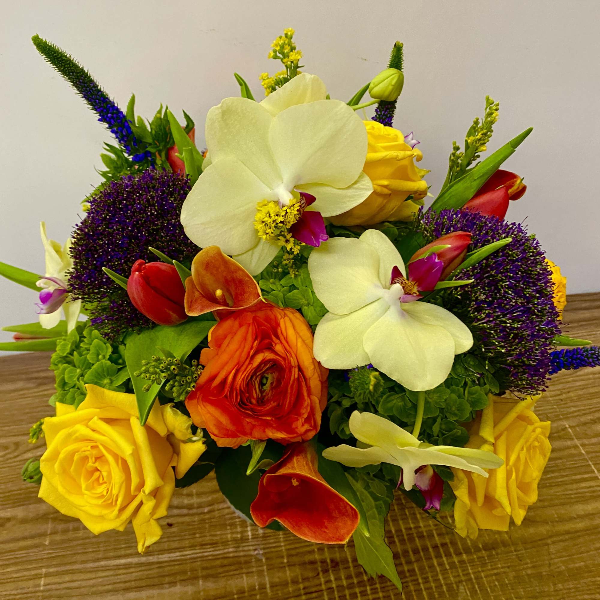 Mixed bouquet with yellow roses, white orchids, and orange calla lilies