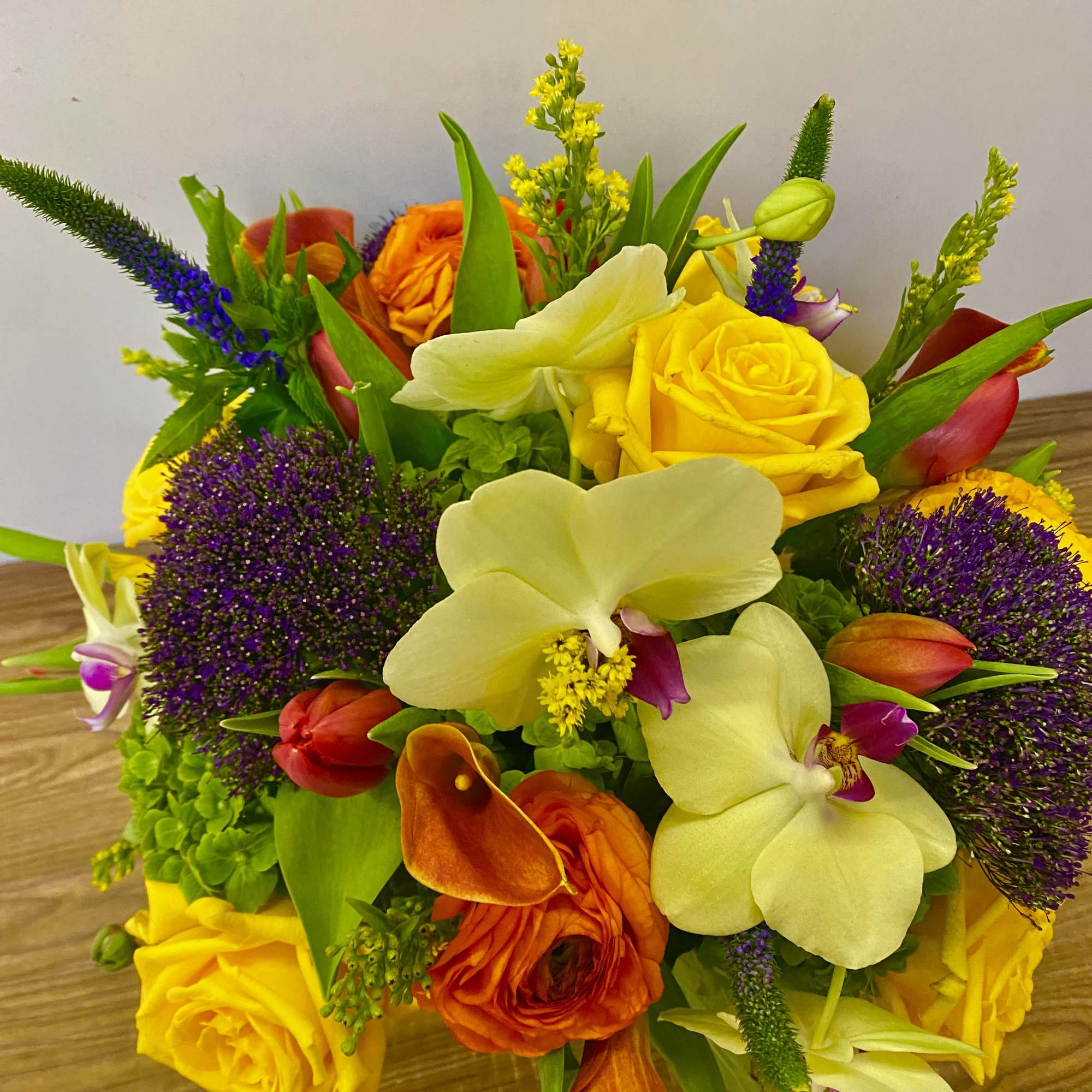 Colorful bouquet with yellow roses, orange flowers, and pale orchids