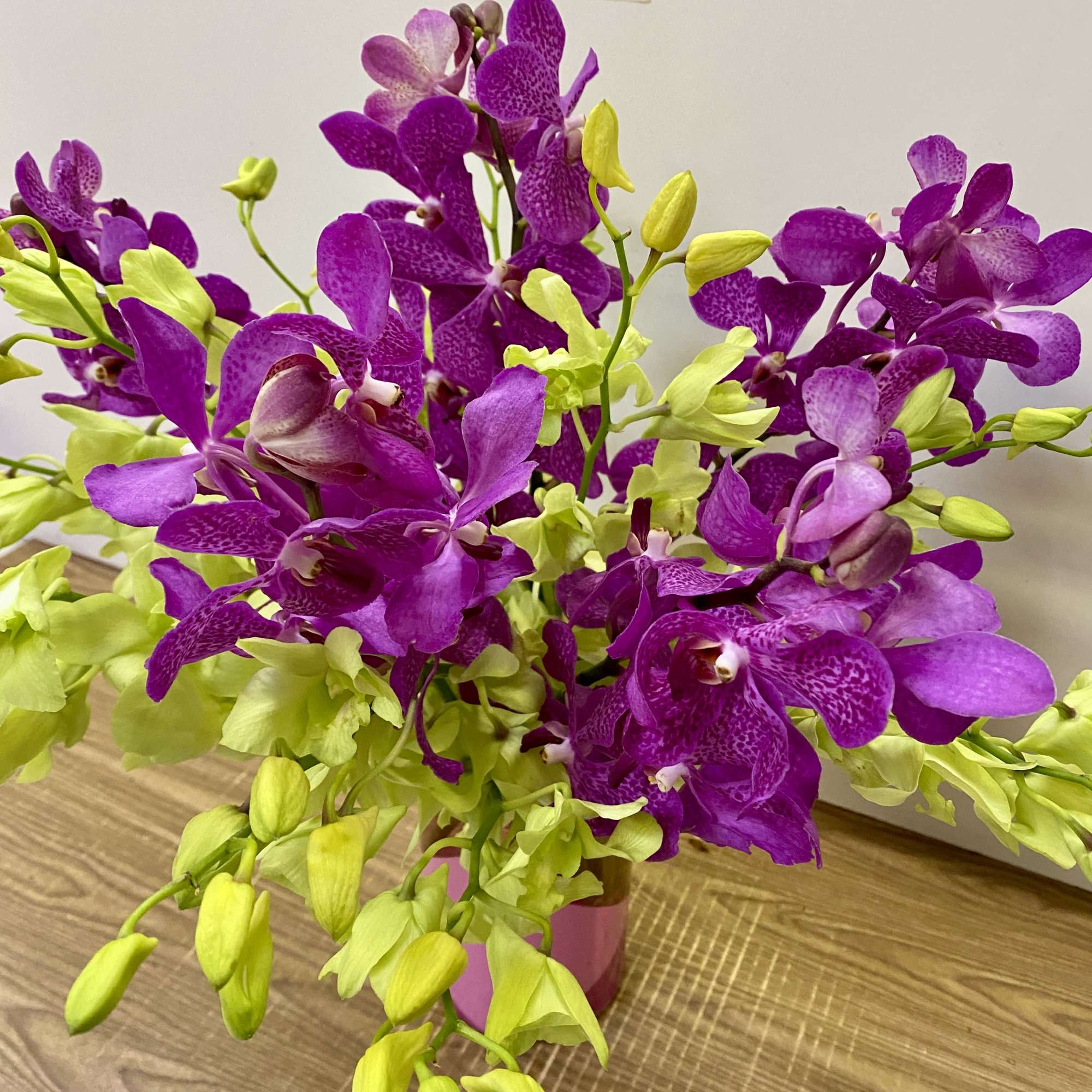 Purple and lime orchid arrangement in a pink vase, photo 2 of 3