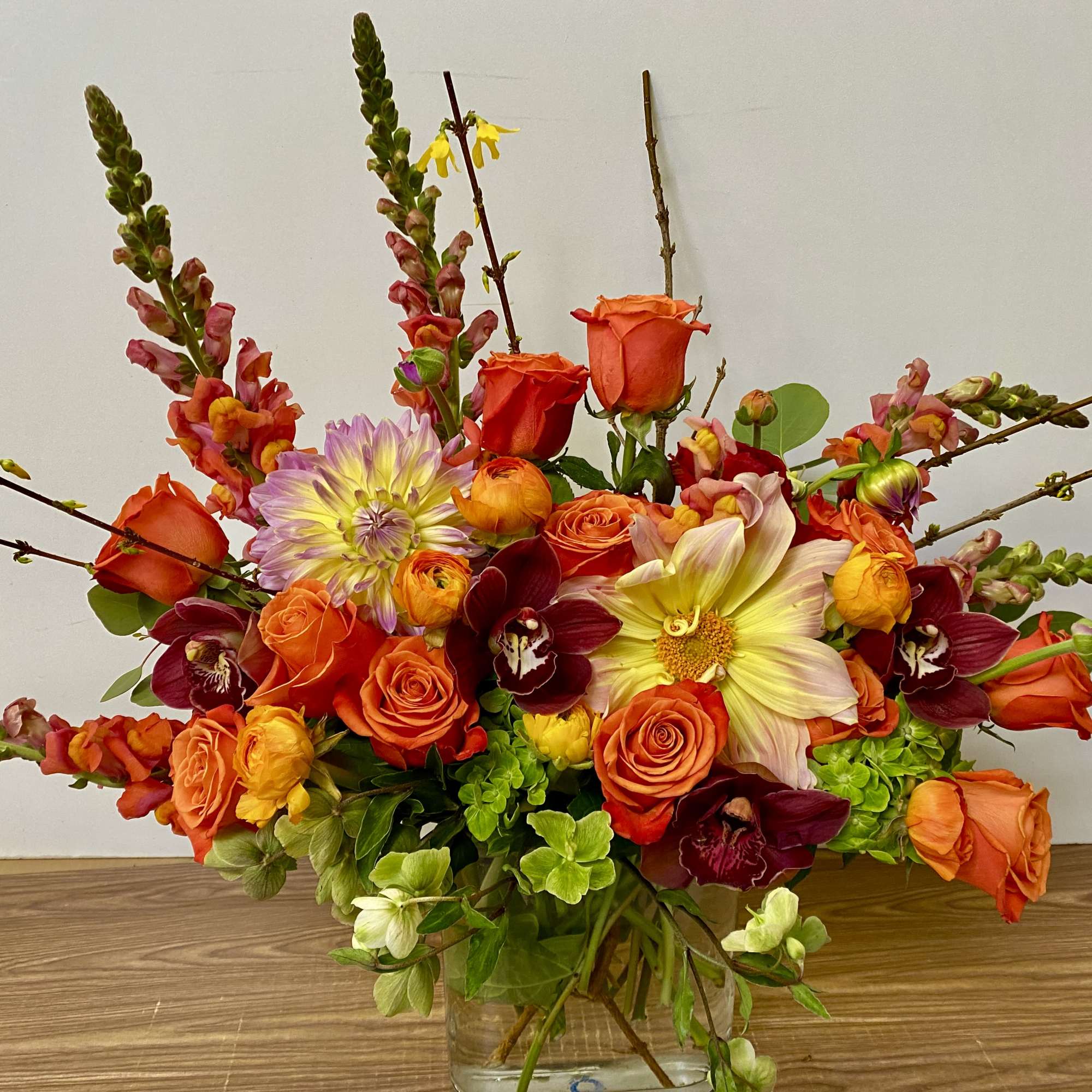 Bright mixed bouquet of orange and burgundy flowers in a clear vase
