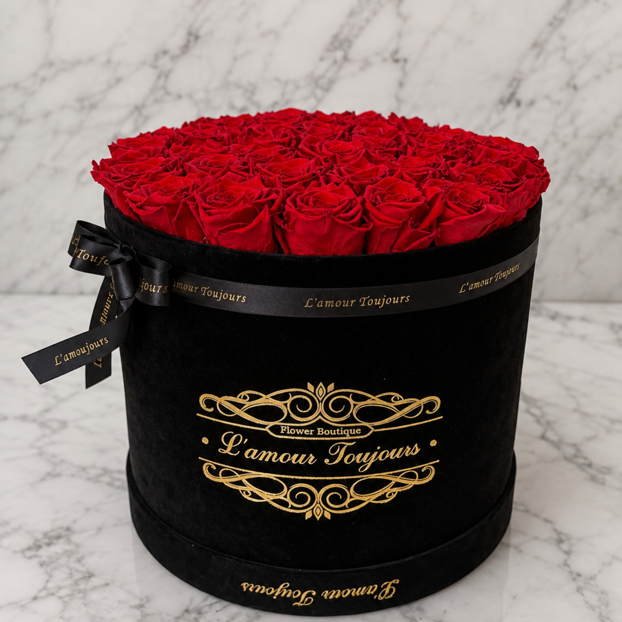 Round box filled with red roses and tied with a black ribbon