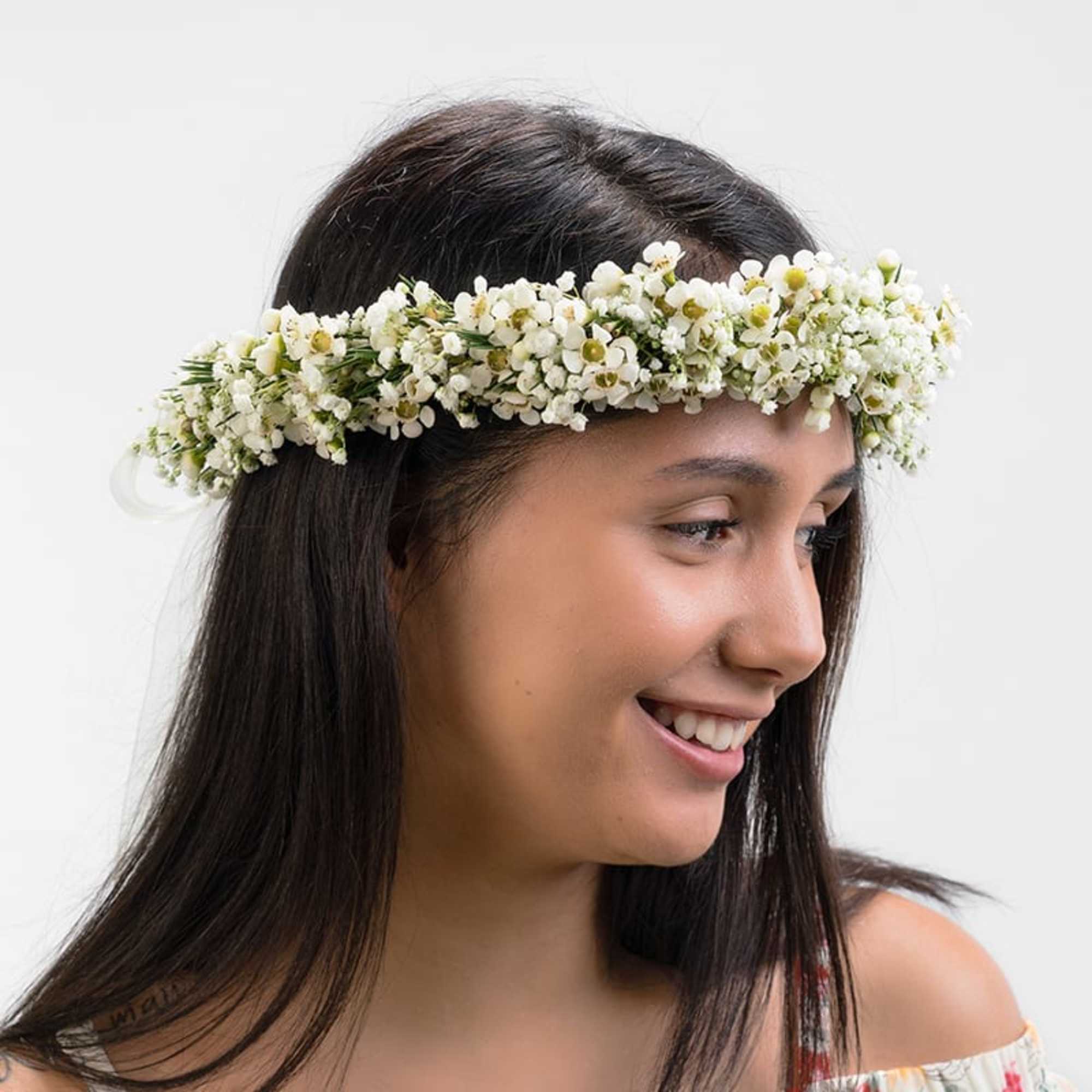 Woman wearing a white flower crown headpiece made of small clustered blossoms