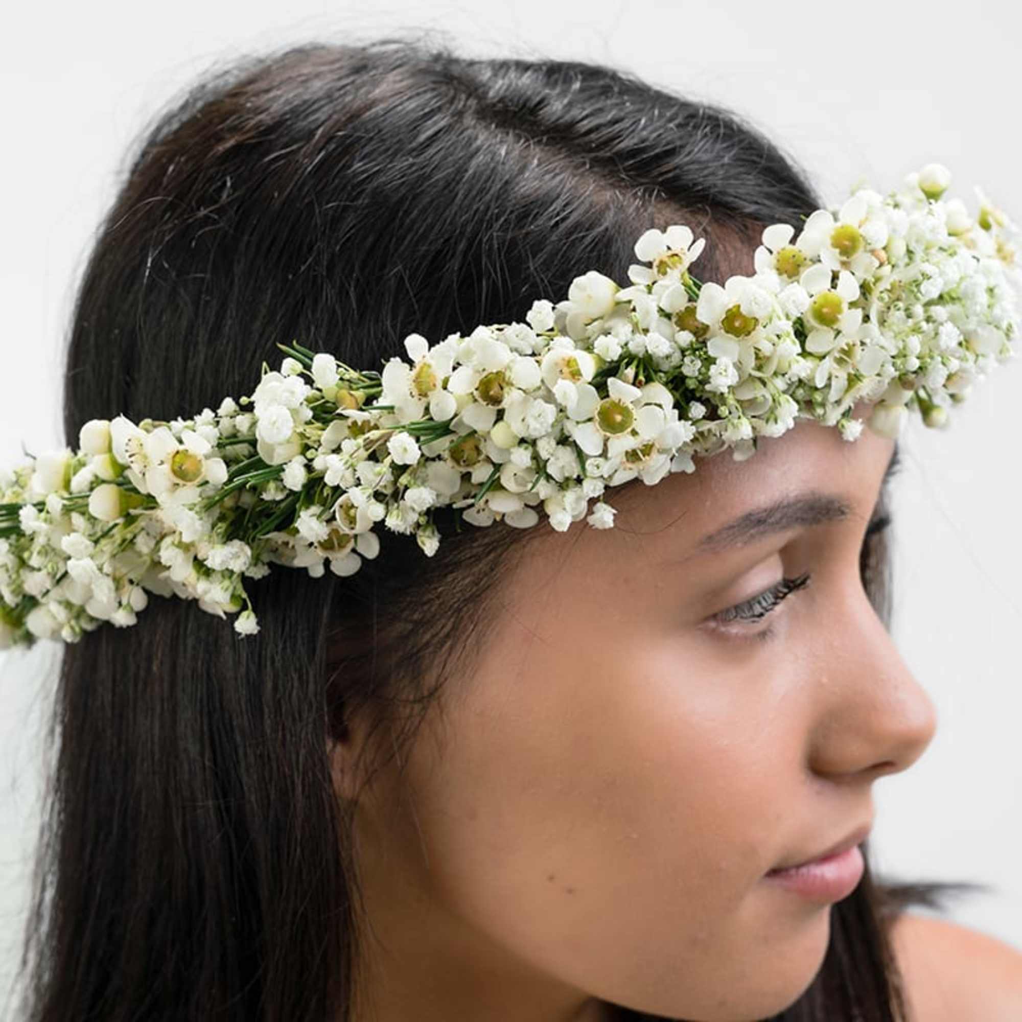 White flower crown of small blossoms worn on a woman’s head