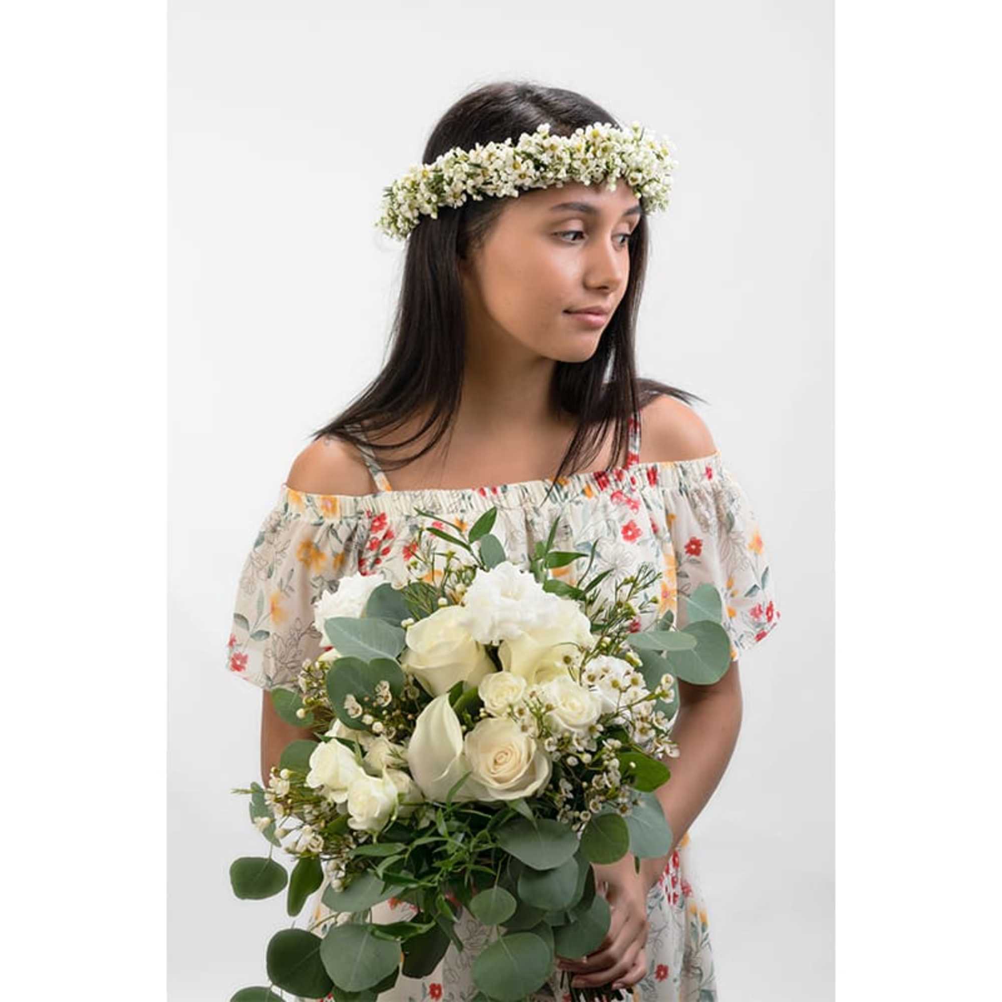 Young woman holding a white rose bouquet and wearing a white flower crown