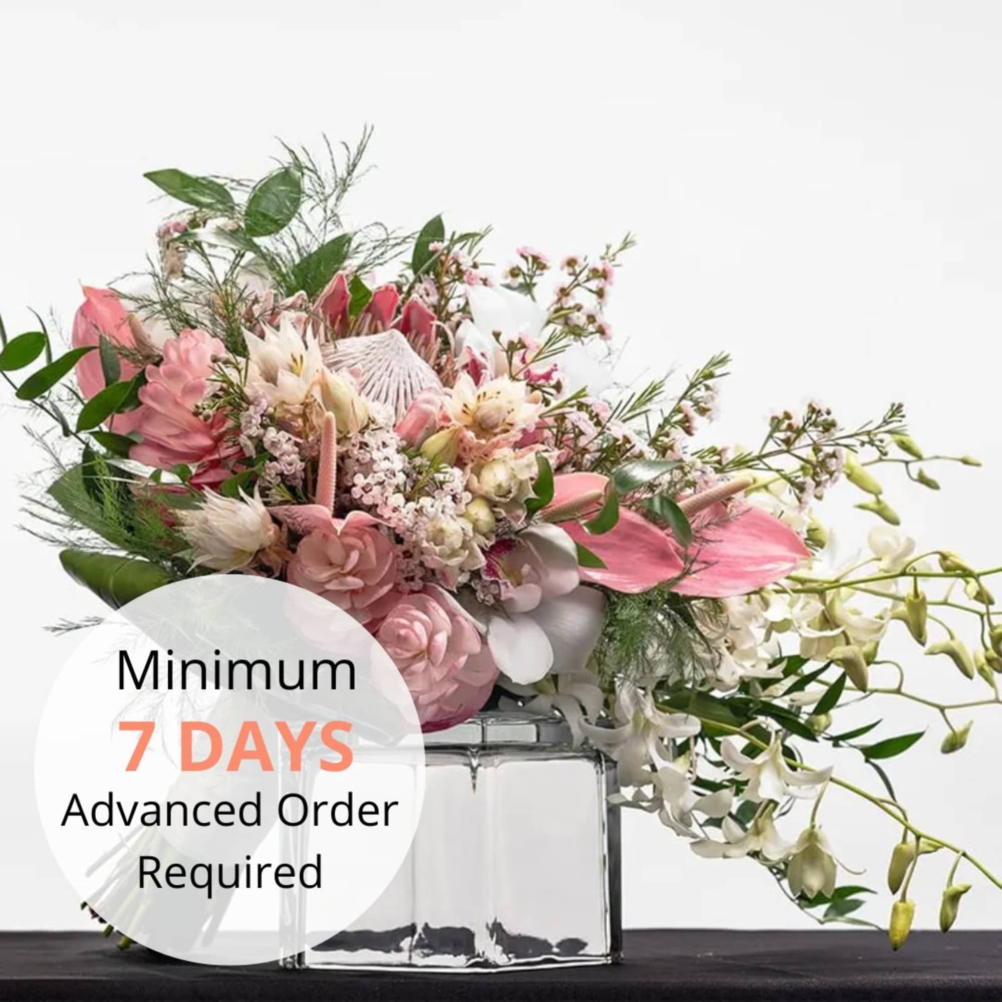 Low pink and white floral arrangement with cascading orchids in a clear glass cube vase