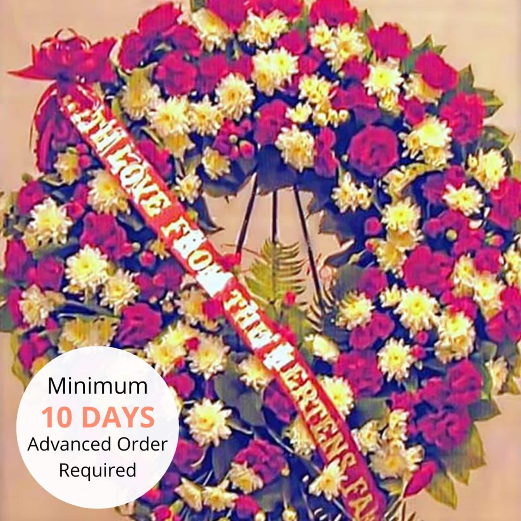 Large red and white standing wreath of roses and chrysanthemums on an easel with a script ribbon.
