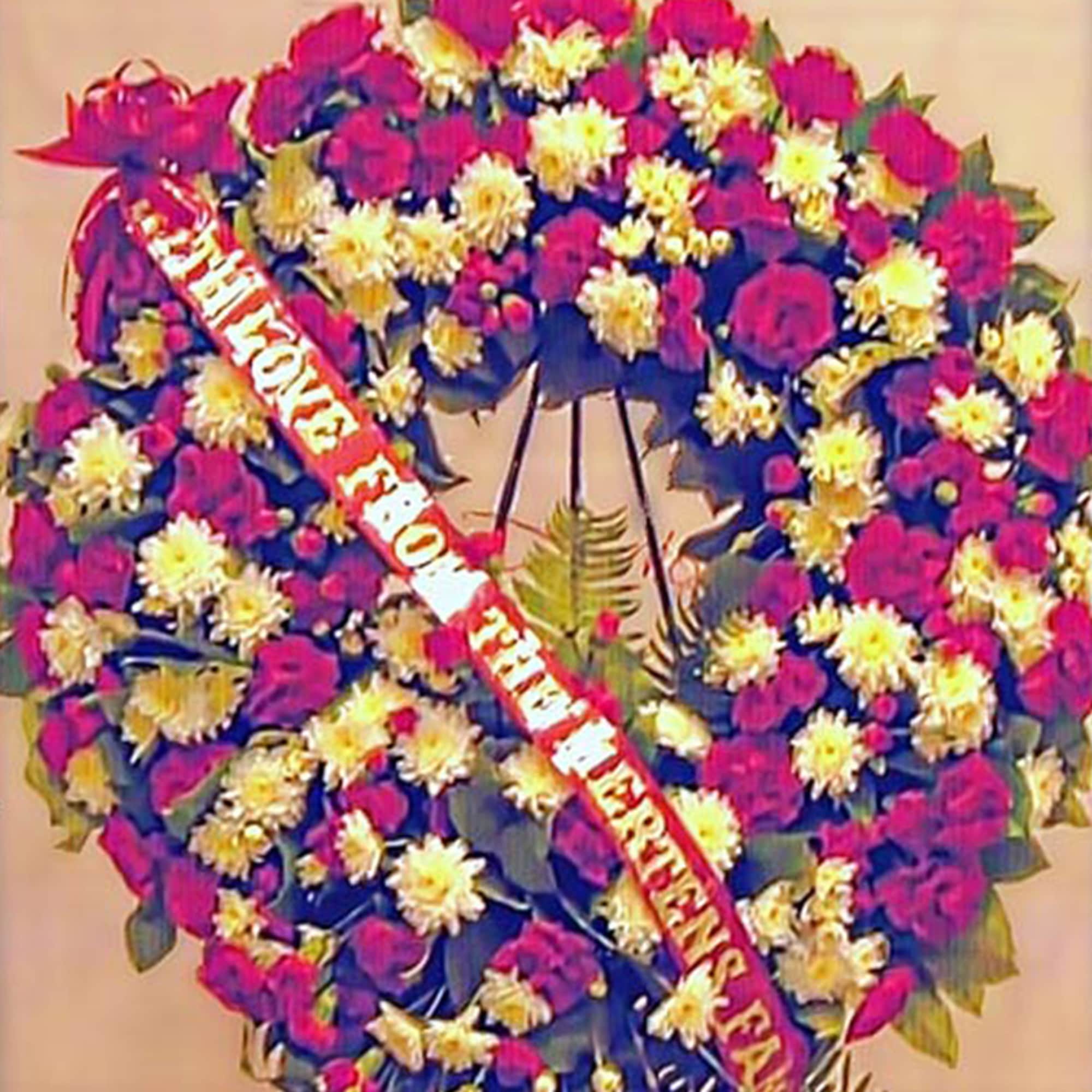 Large red and white floral wreath with a message ribbon on a stand