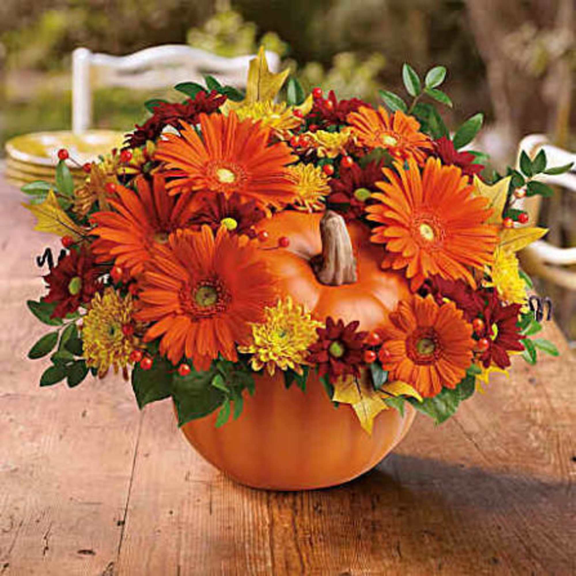 Orange and yellow flowers arranged in a pumpkin-shaped container