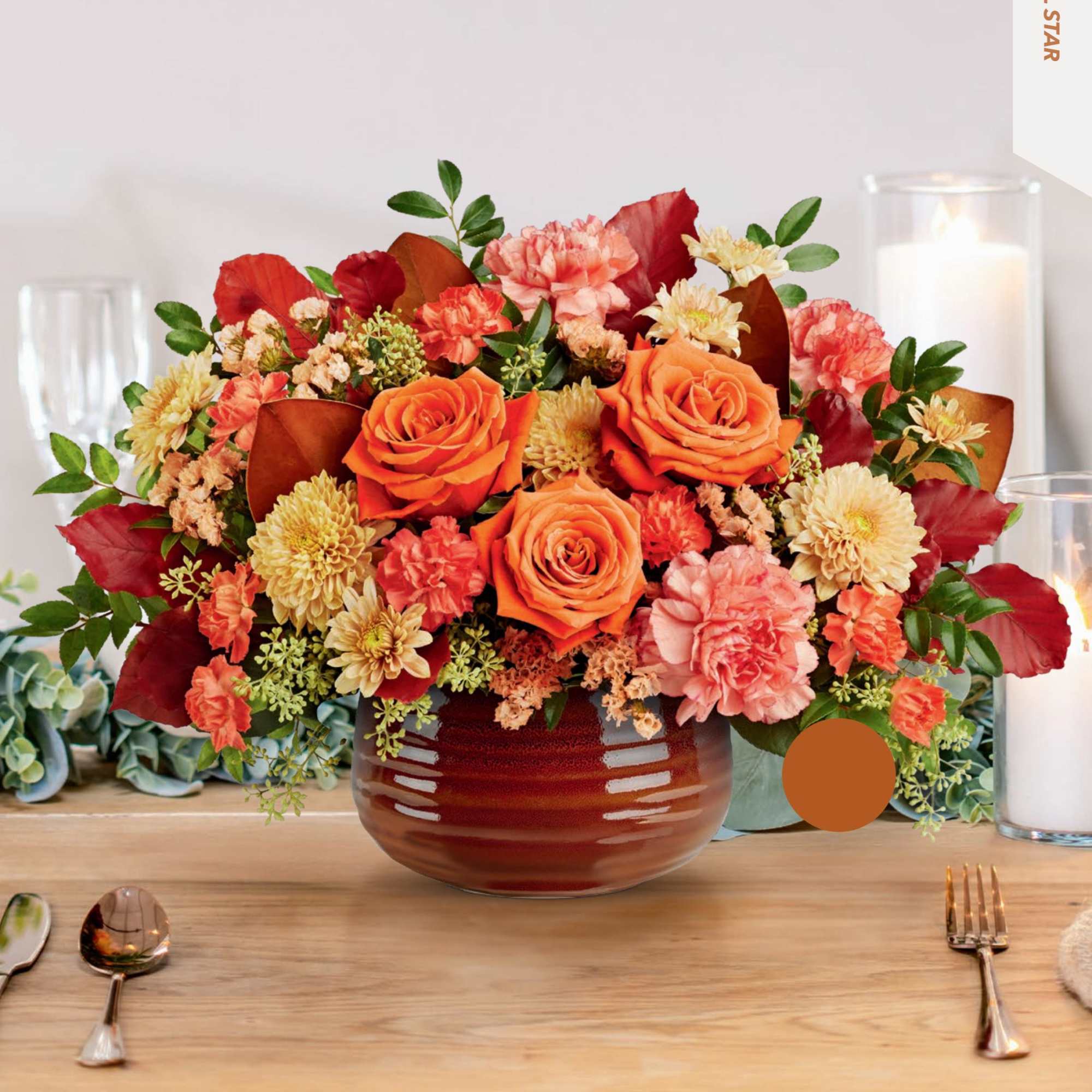 Orange and pink floral arrangement in a round vase on a table