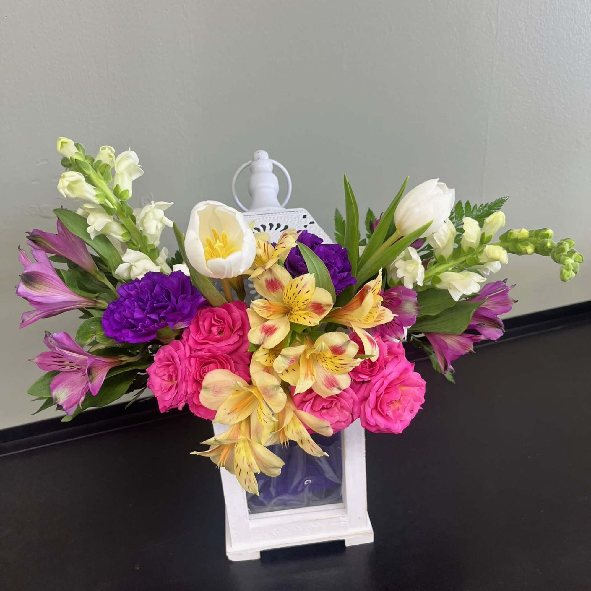 Colorful bouquet in a white lantern vase with pink, purple, yellow, and white flowers