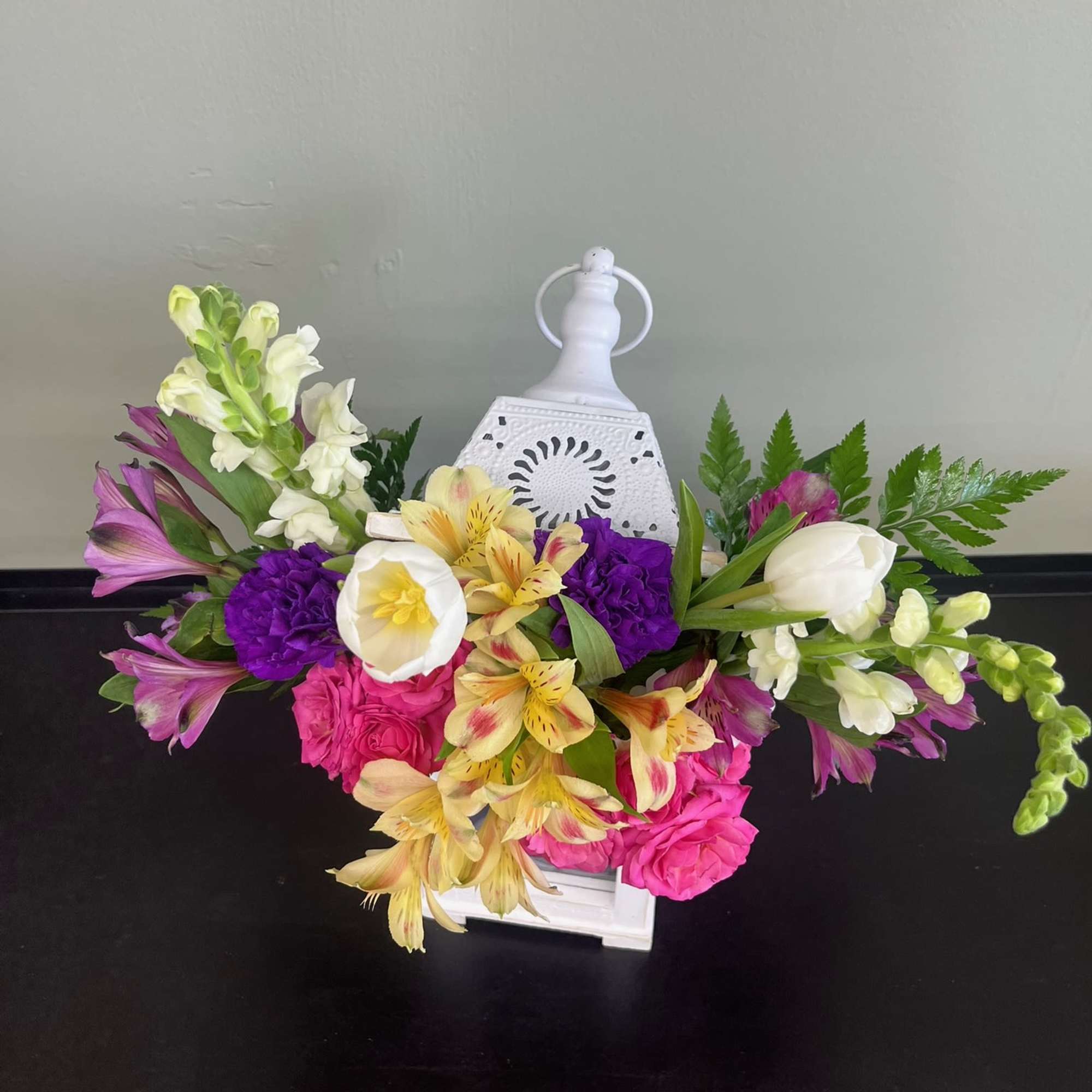 Colorful floral arrangement in a white lantern-style container