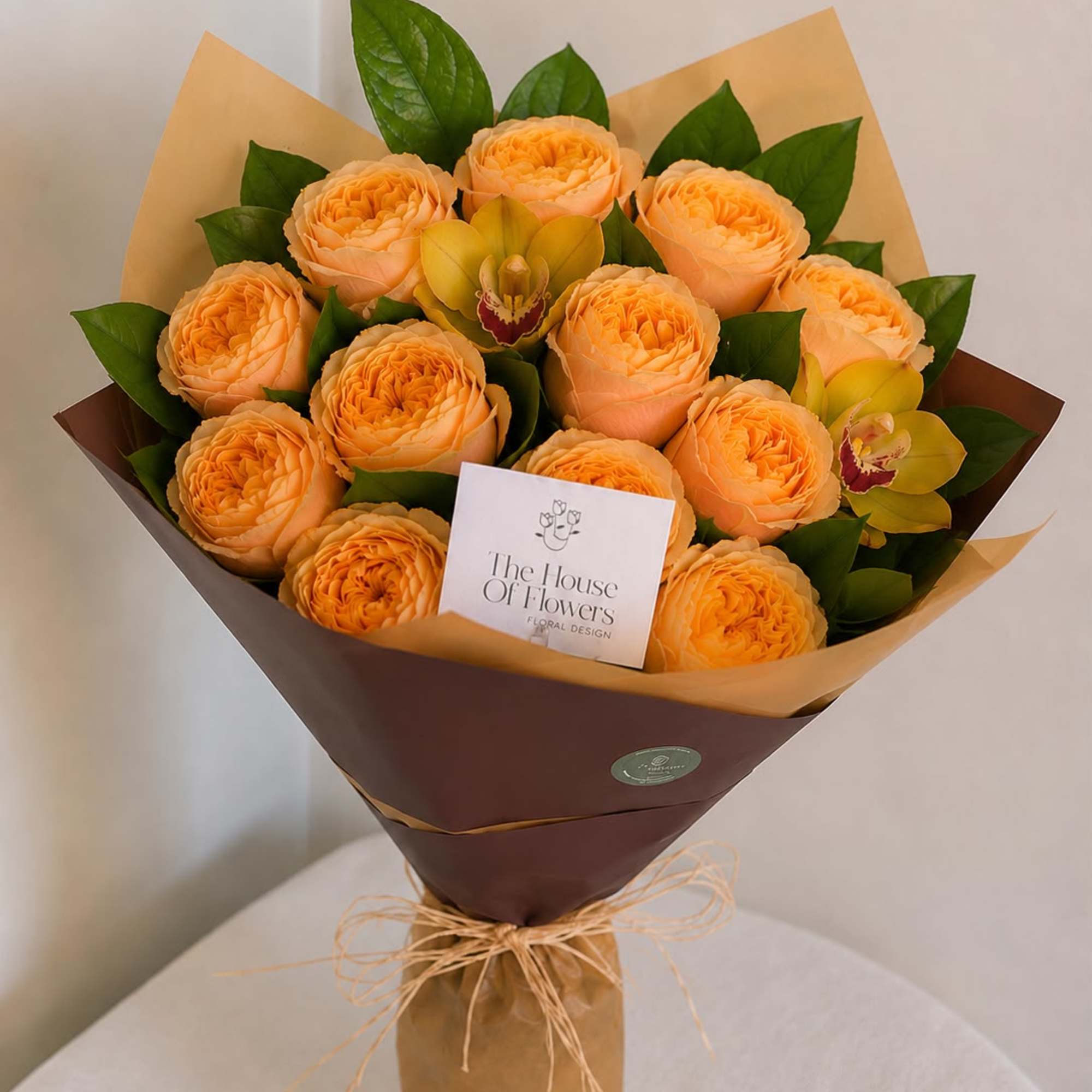 Bouquet of peach roses with yellow orchids wrapped in brown paper