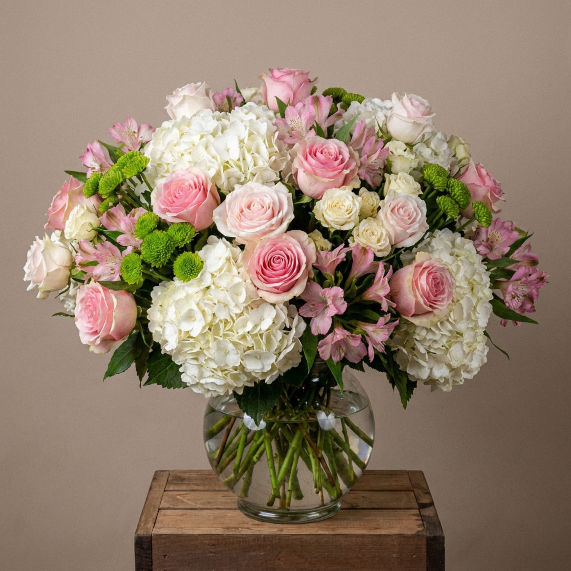 Pink and white roses with hydrangeas in a clear glass vase