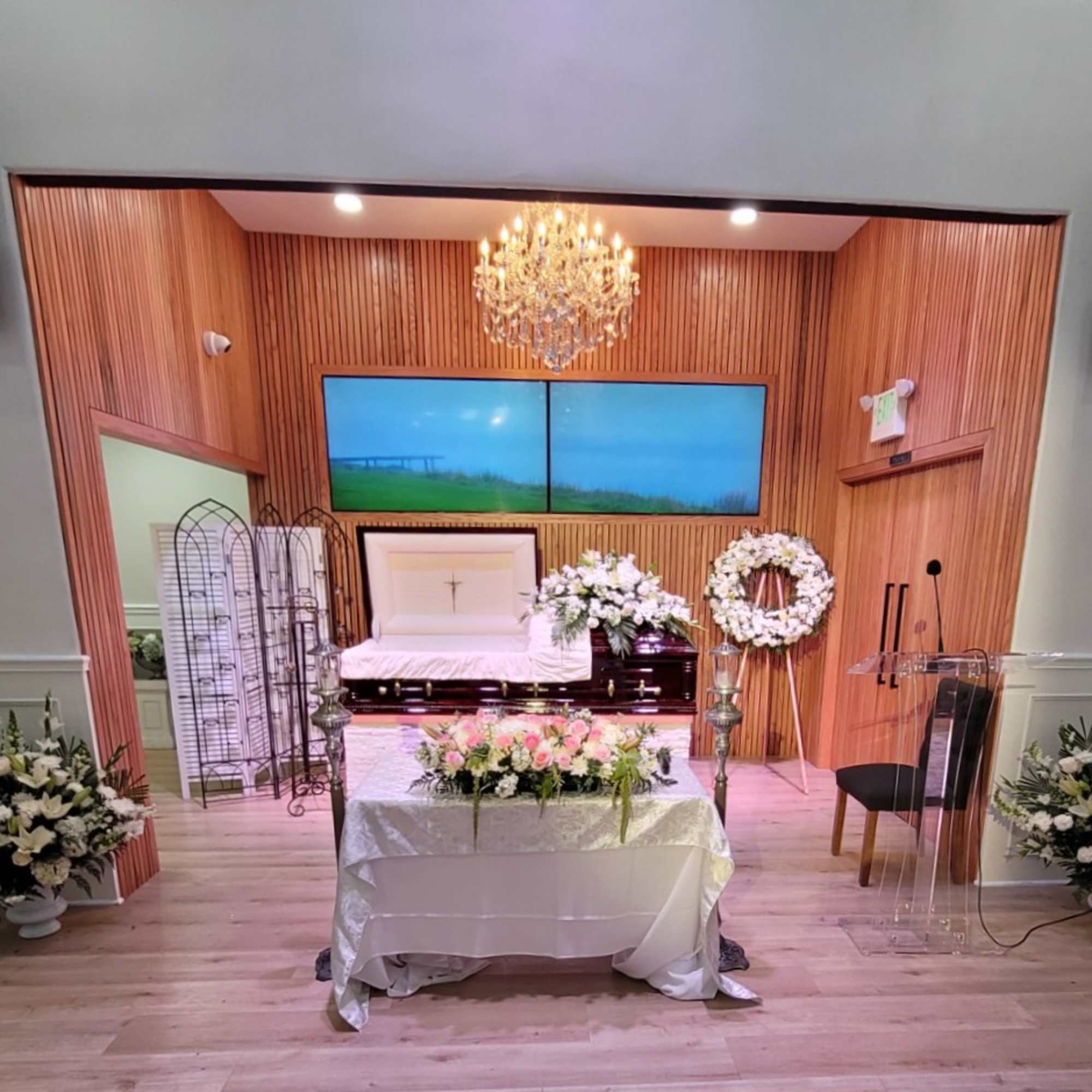 Funeral chapel setup with white floral arrangements around a casket