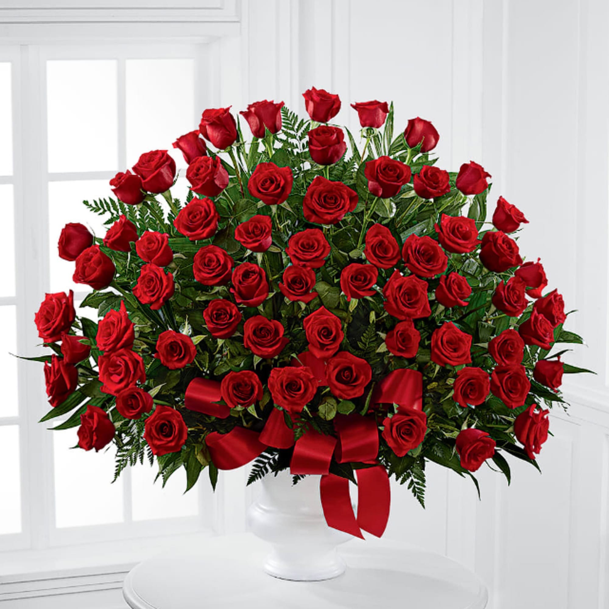 Large bouquet of red roses in a white vase with a red ribbon