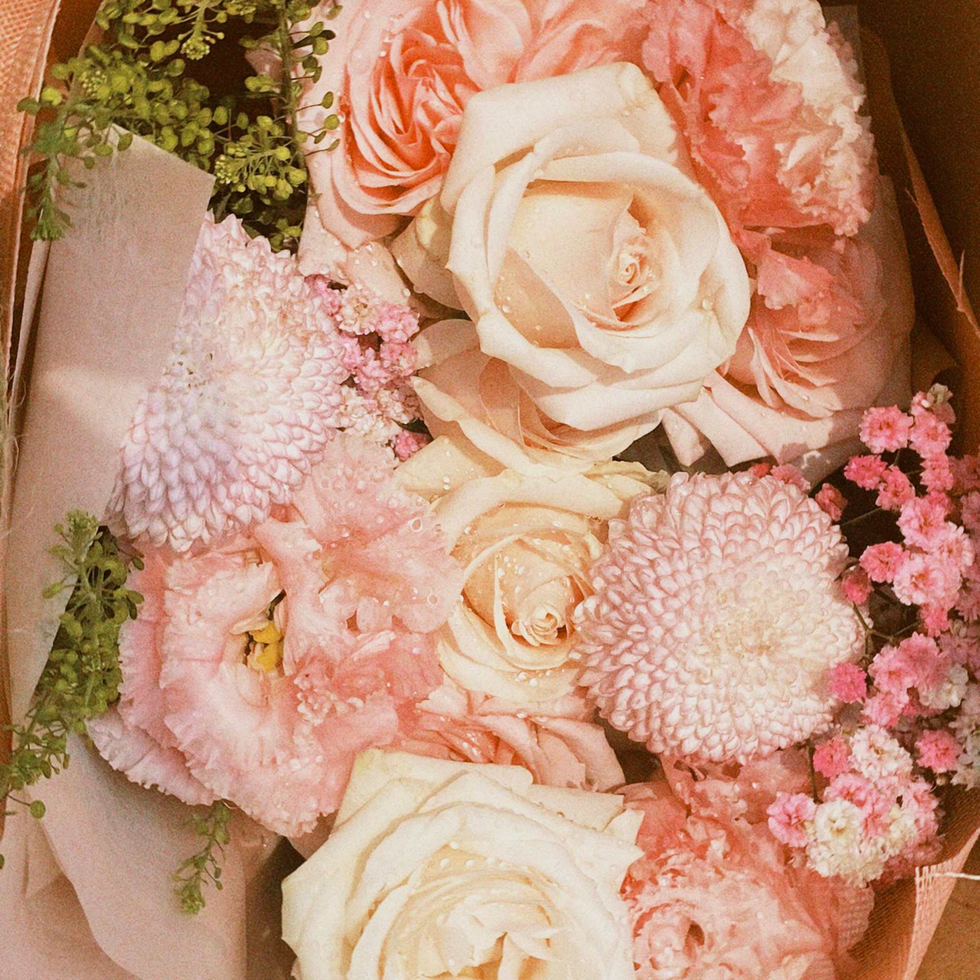 Bouquet of blush and cream roses with pink blooms wrapped in peach paper