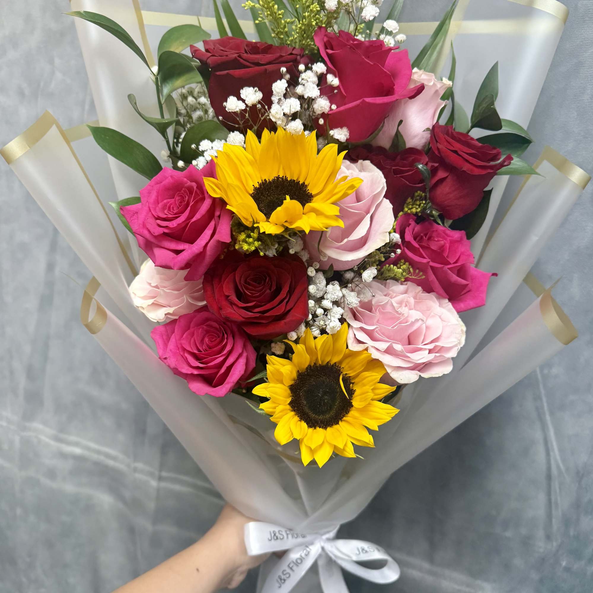 Bouquet of roses and sunflowers wrapped in translucent paper