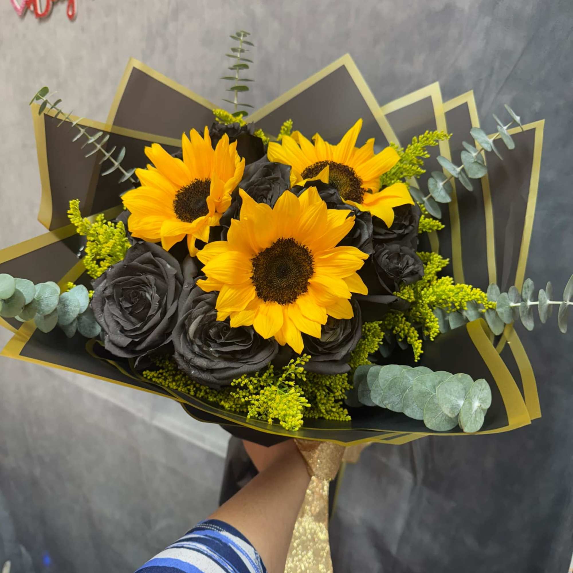 Bouquet of yellow sunflowers and black roses wrapped in black paper