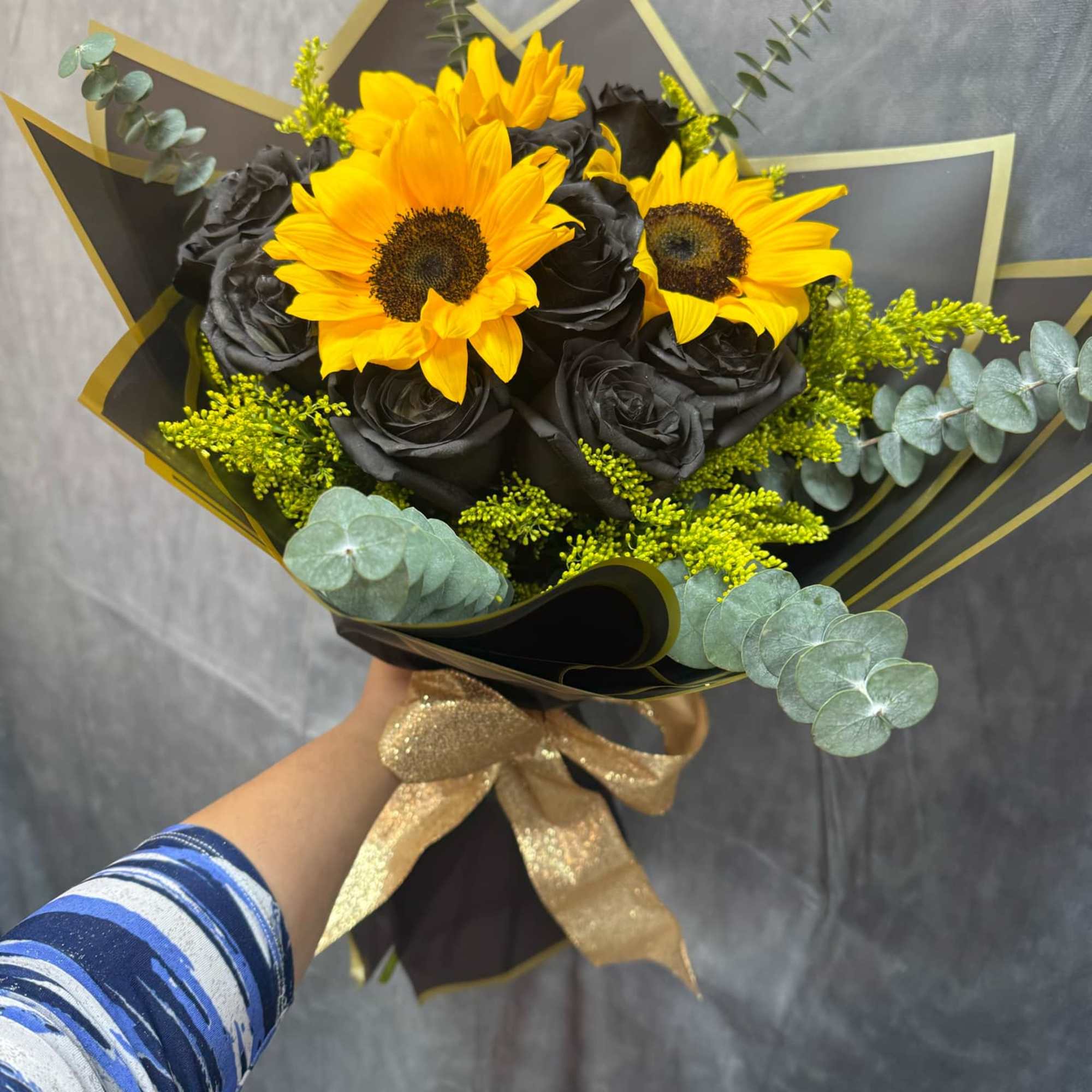 Bouquet of yellow sunflowers and black roses wrapped in dark paper