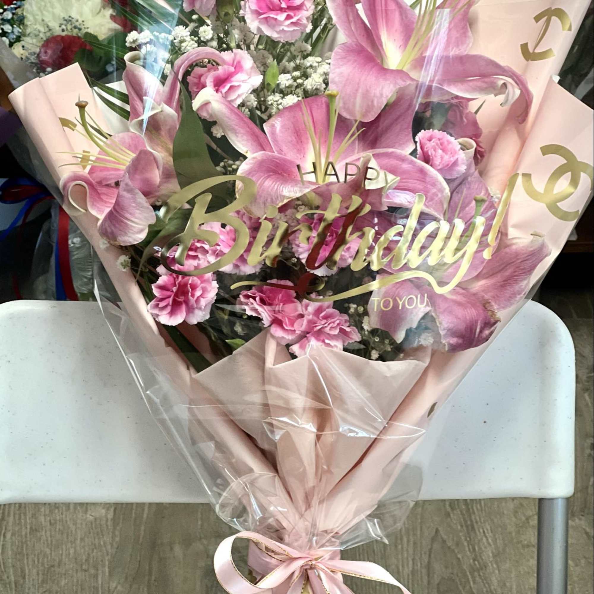 Pink lily and carnation bouquet wrapped in blush paper with a ribbon, photo 2 of 3