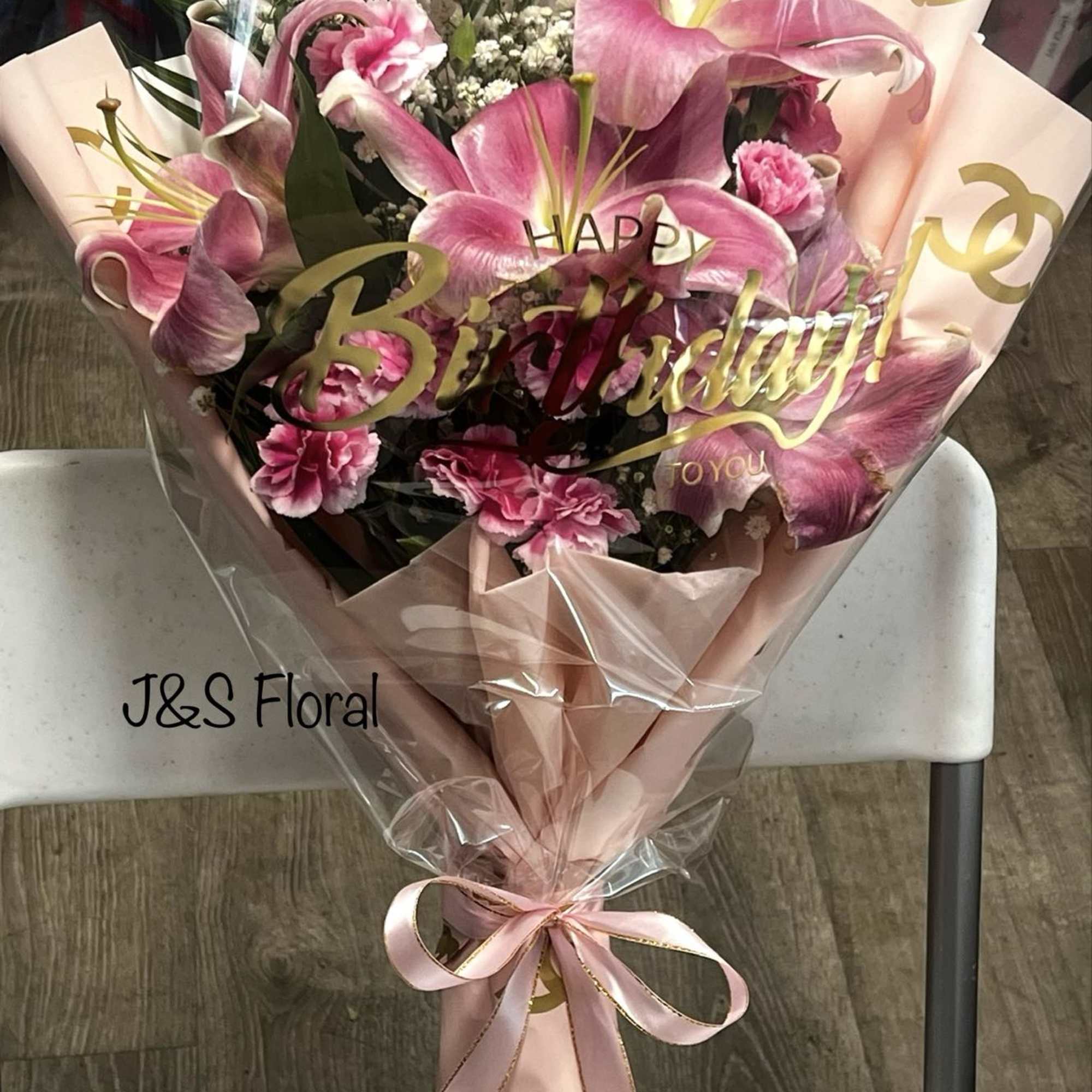 Pink lily and carnation bouquet wrapped in blush paper with a ribbon, photo 3 of 3