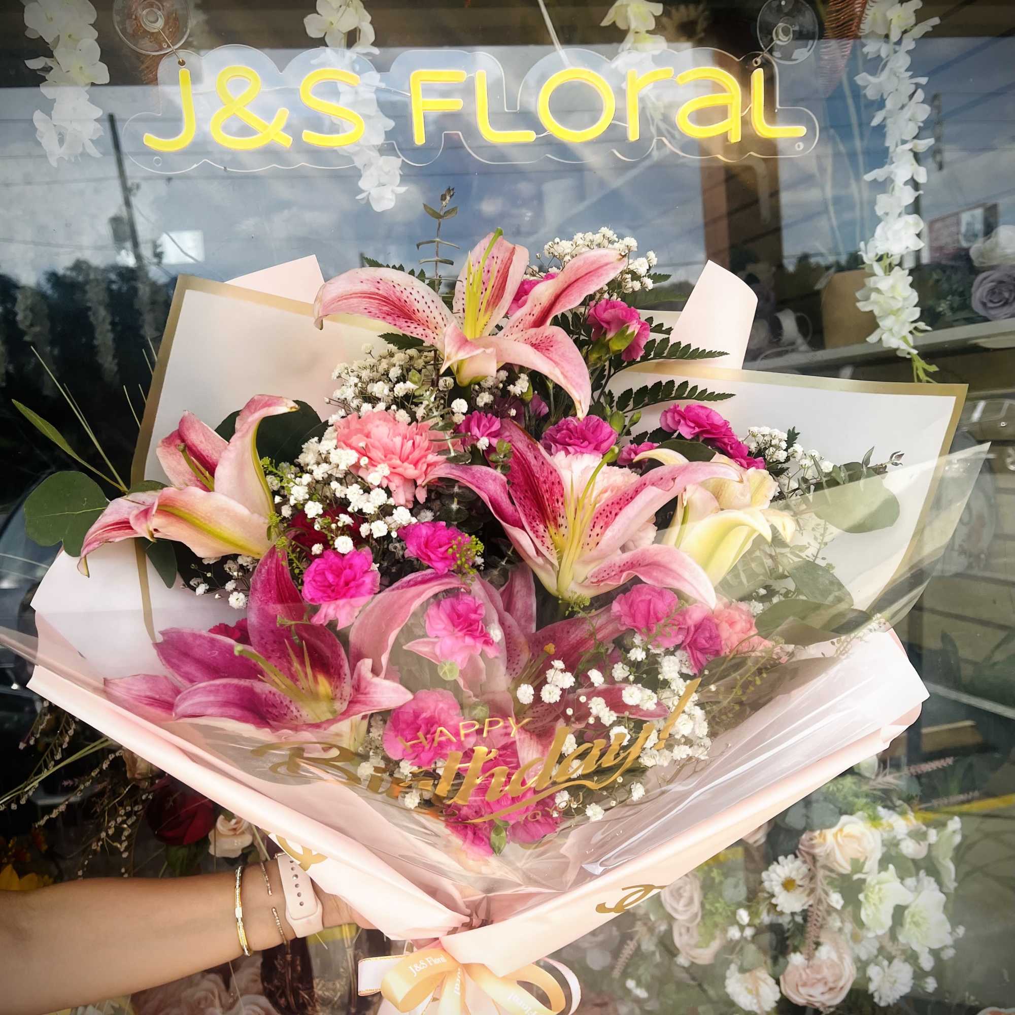 Pink lily bouquet with baby’s breath and a birthday ribbon